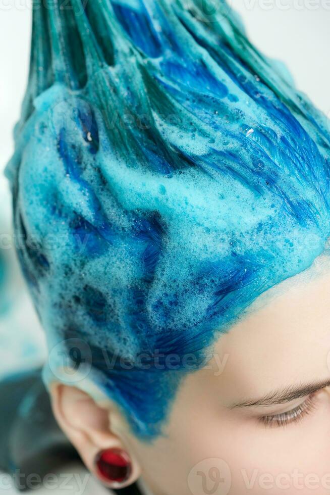 fechar-se Visão do cabeça do mulher com azul cabelo enquanto lavagem cabeça dentro beleza salão foto