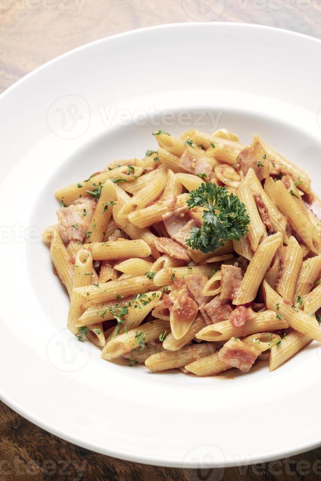 Molho de tomate e presunto penne amatriciana macarrão no fundo da mesa de madeira foto