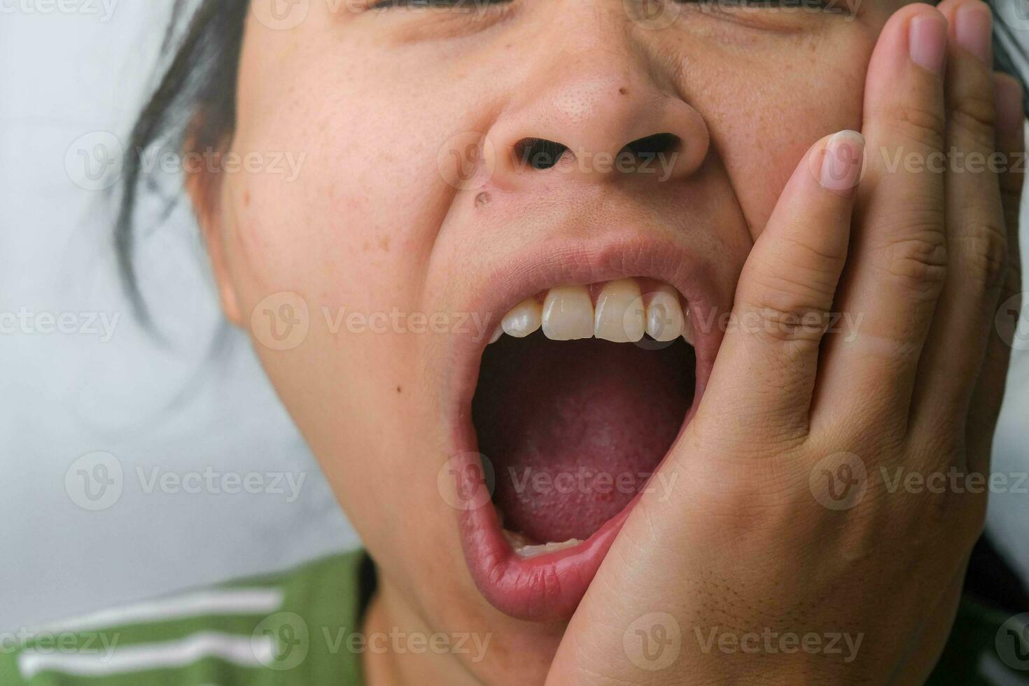 ásia mulher segurando dela mão em dela bochecha sentindo-me dor de dente, dente decair, gengivite ou mau respiração problema. dor de dente e oral saúde conceito. foto