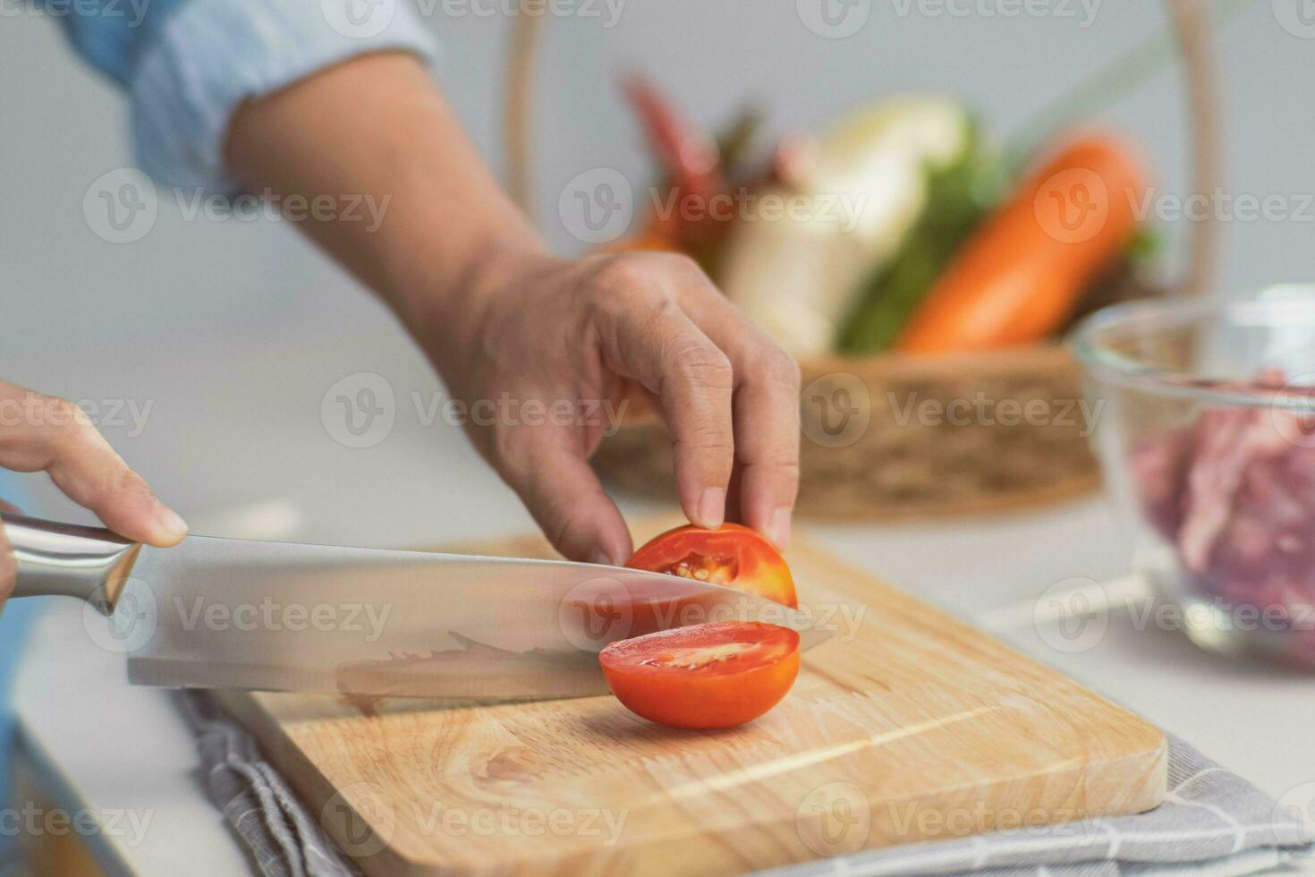 cozinhando - chef mãos estão corte tomates em a cortar borda dentro a cozinha. preparando carne de porco estoque com legumes caldo dentro uma Panela. caseiro caldo receita. foto