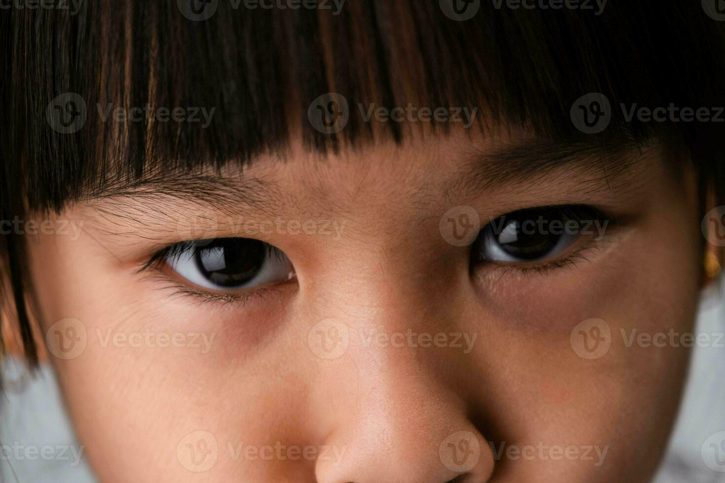 lindo olhos do uma pequeno ásia menina fechar-se. Tiros na Cabeça cortada imagem do uma garotas olhos estão Bravo expressão. foto