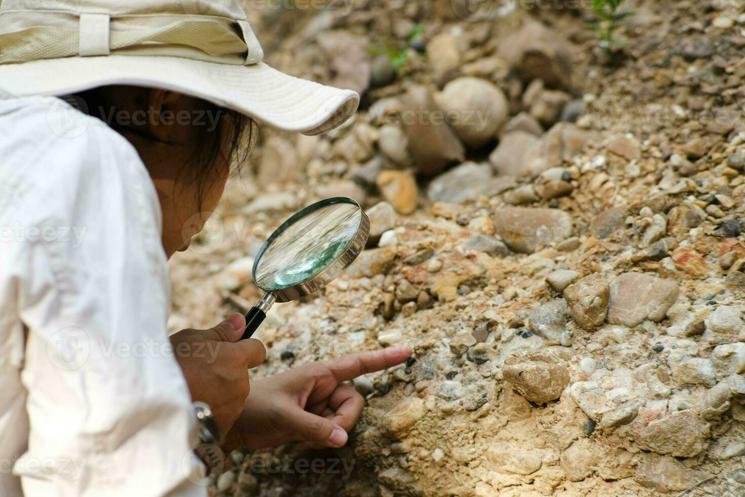 fêmea geólogo usando ampliação vidro para examinar e analisar pedra, solo, areia dentro natureza. arqueólogos explorar a campo. de Meio Ambiente e ecologia pesquisar. foto