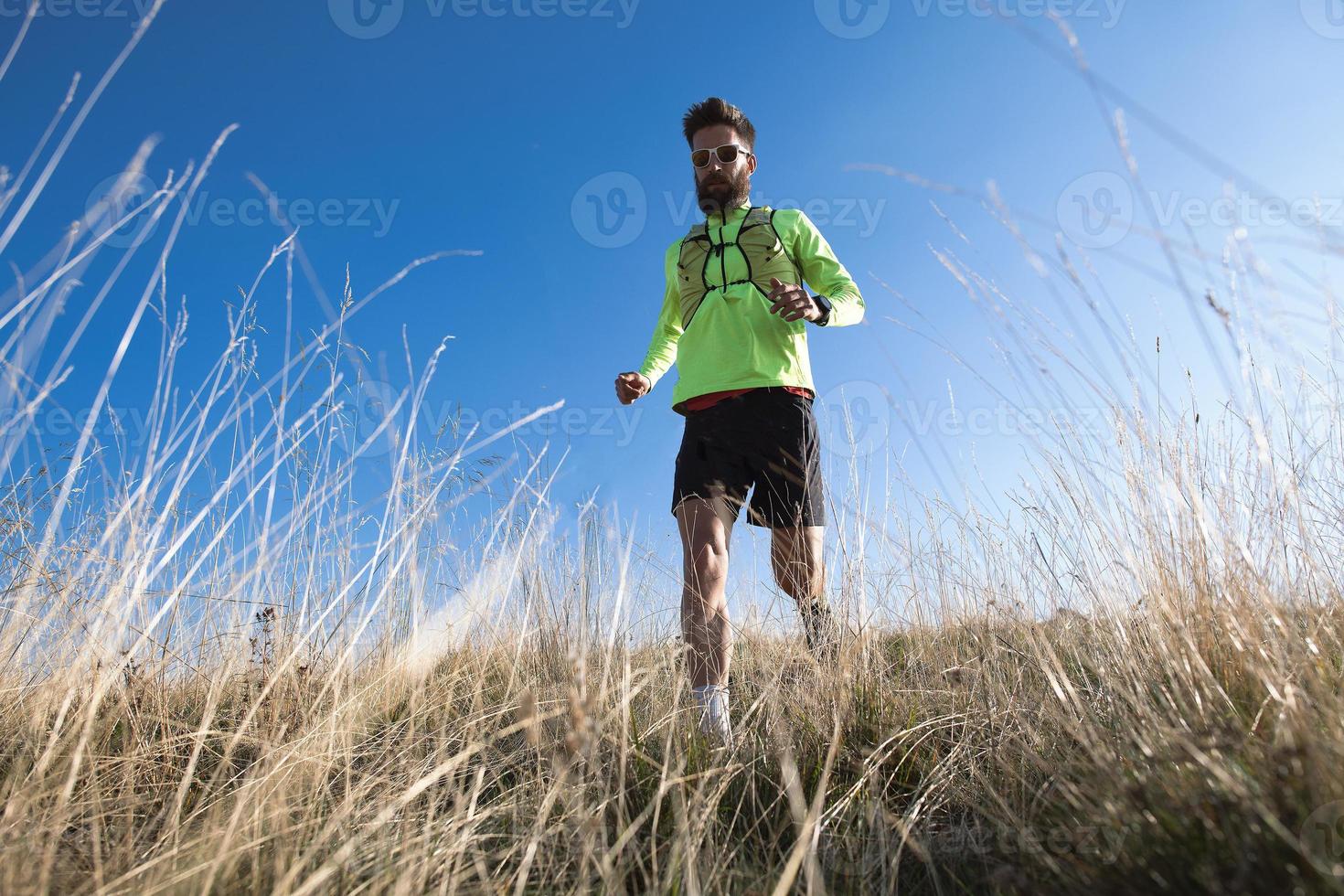 montanha correndo atleta ladeira abaixo entre os prados de outono foto