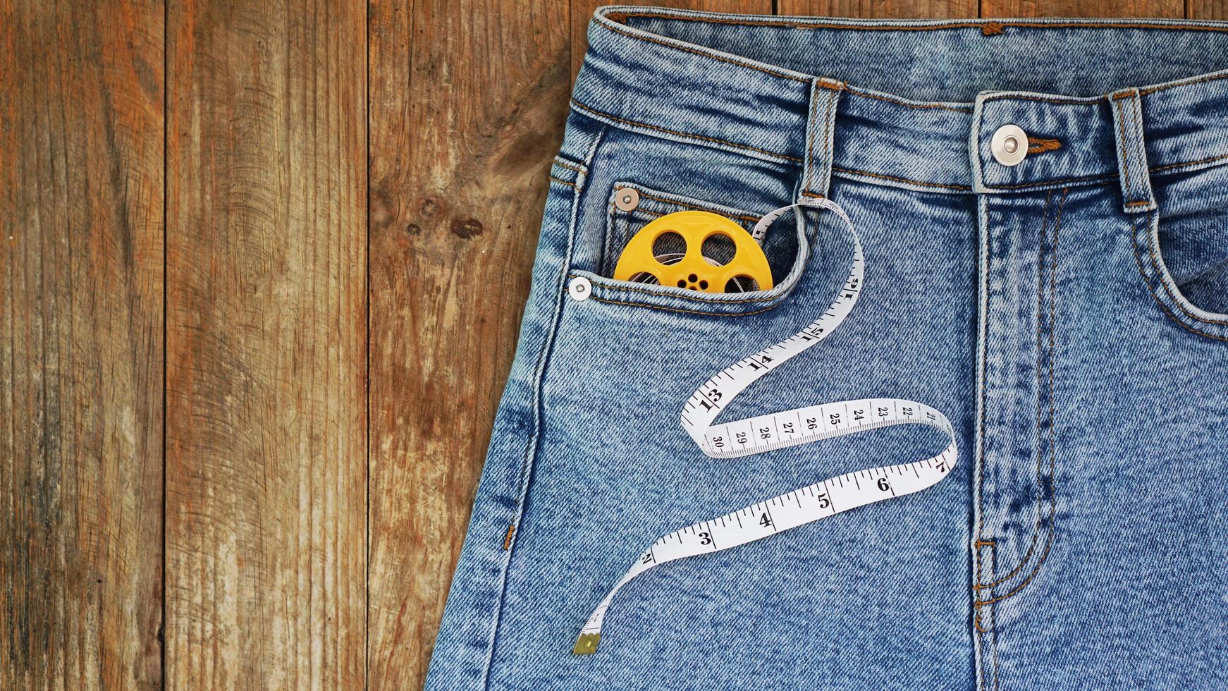 jeans e uma fita métrica. conceito de emagrecimento ou costura jeans foto