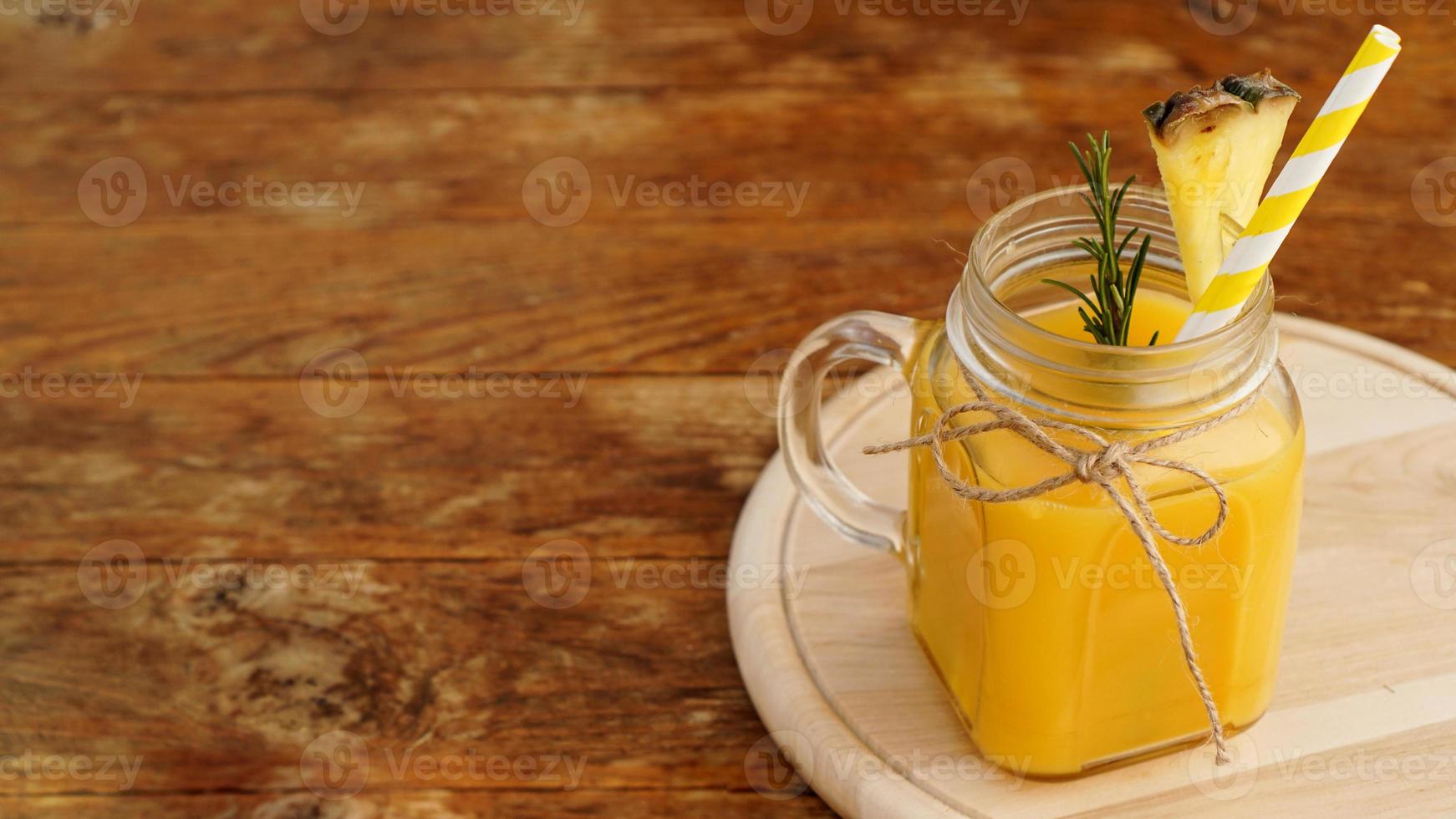 suco de abacaxi em uma jarra de vidro. Fatias de abacaxi decoram a bebida foto