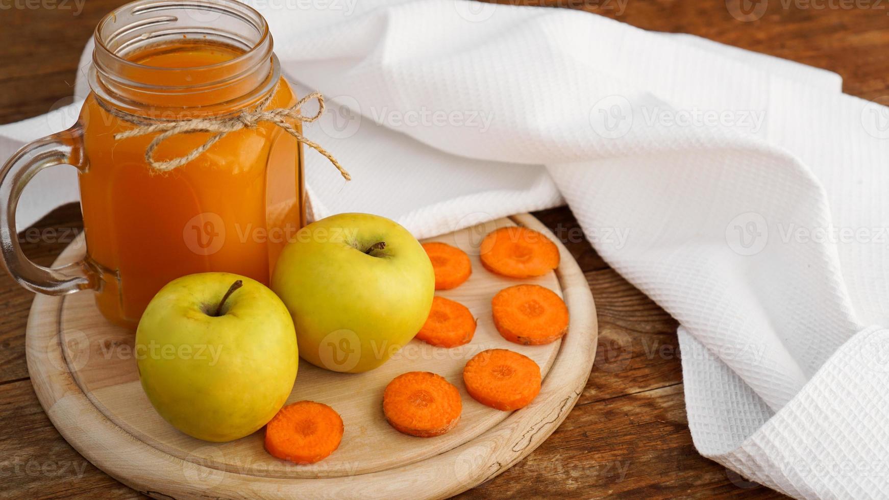 suco de maçã e cenoura em vidro, vegetais frescos e frutas em madeira foto