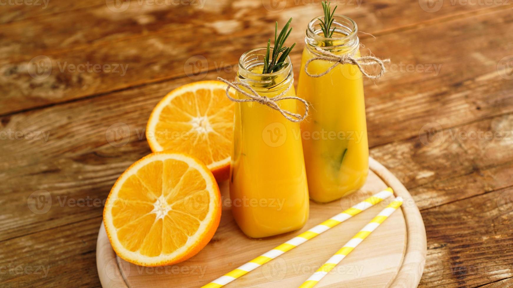 suco de laranja em garrafas de vidro. o suco é decorado foto