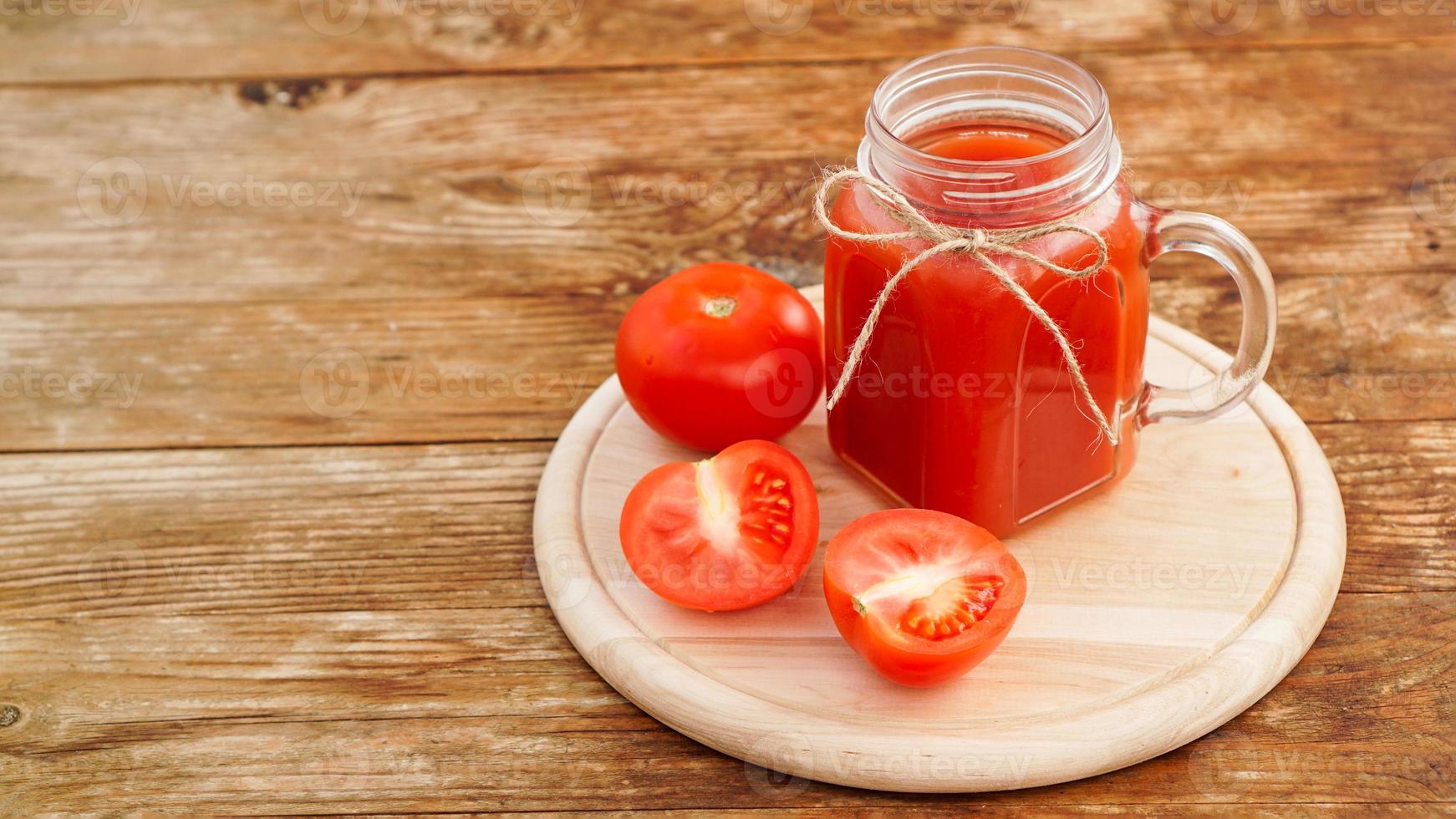 copo de suco de tomate na mesa de madeira. suco de tomate fresco foto