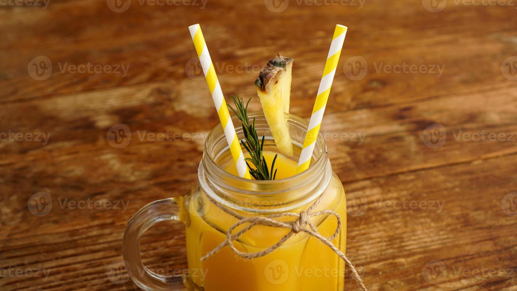 suco de abacaxi em uma jarra de vidro. Fatias de abacaxi decoram a bebida foto