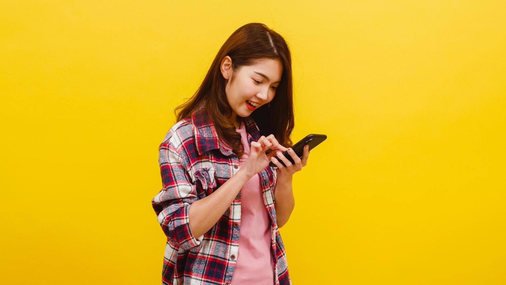mulher asiática usando telefone com expressão positiva, sorri amplamente. foto