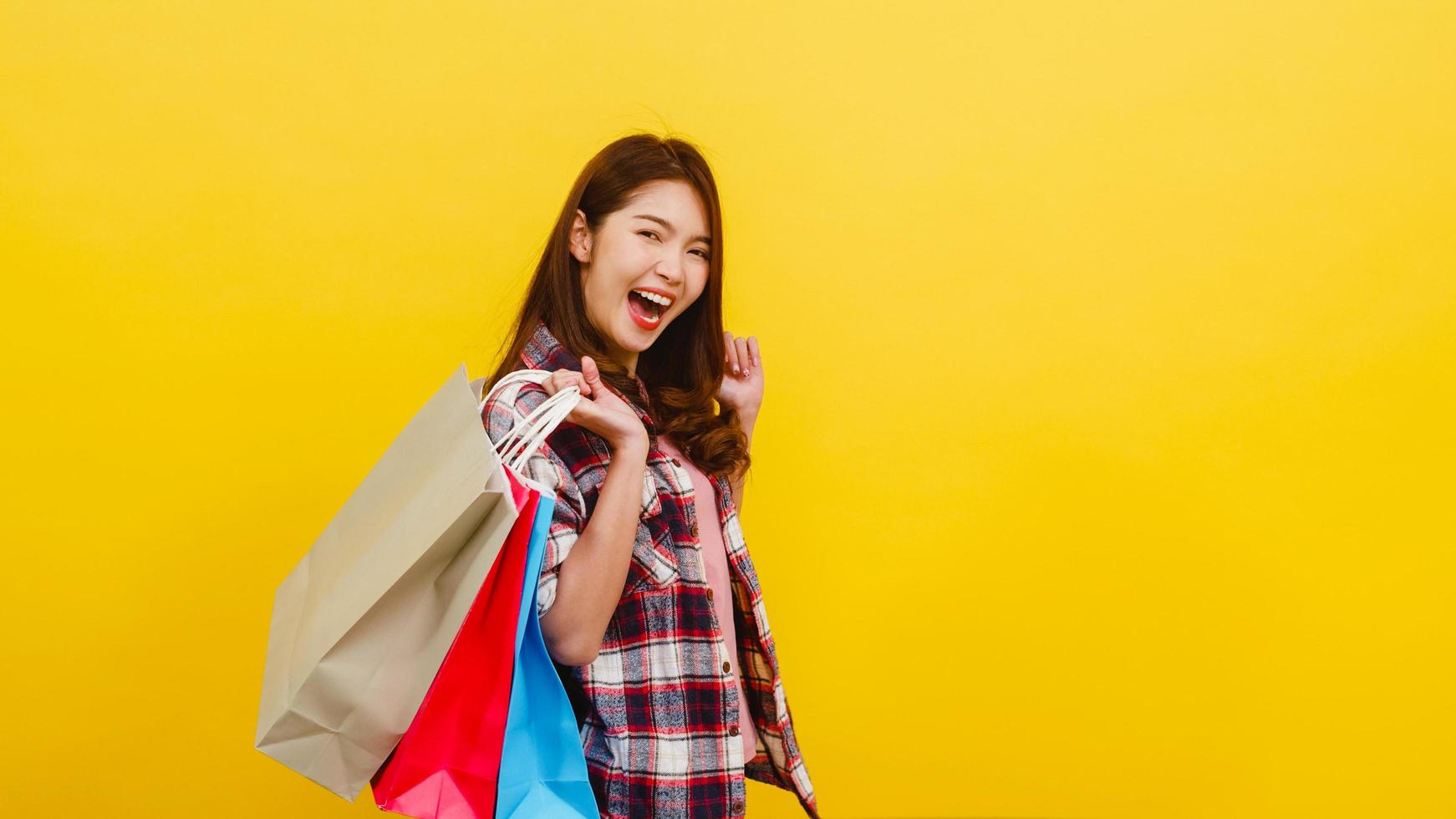 feliz jovem asiática carregando sacolas de compras com a mão, levantando-se. foto