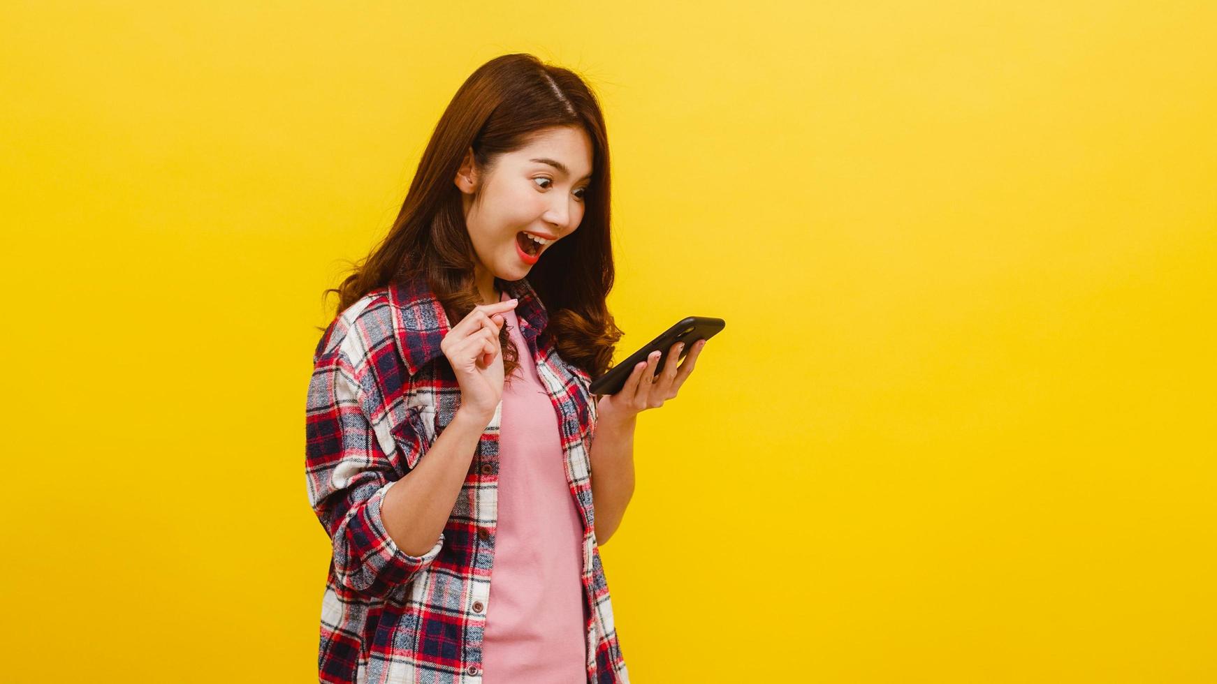 mulher asiática usando telefone com expressão positiva, sorri amplamente. foto