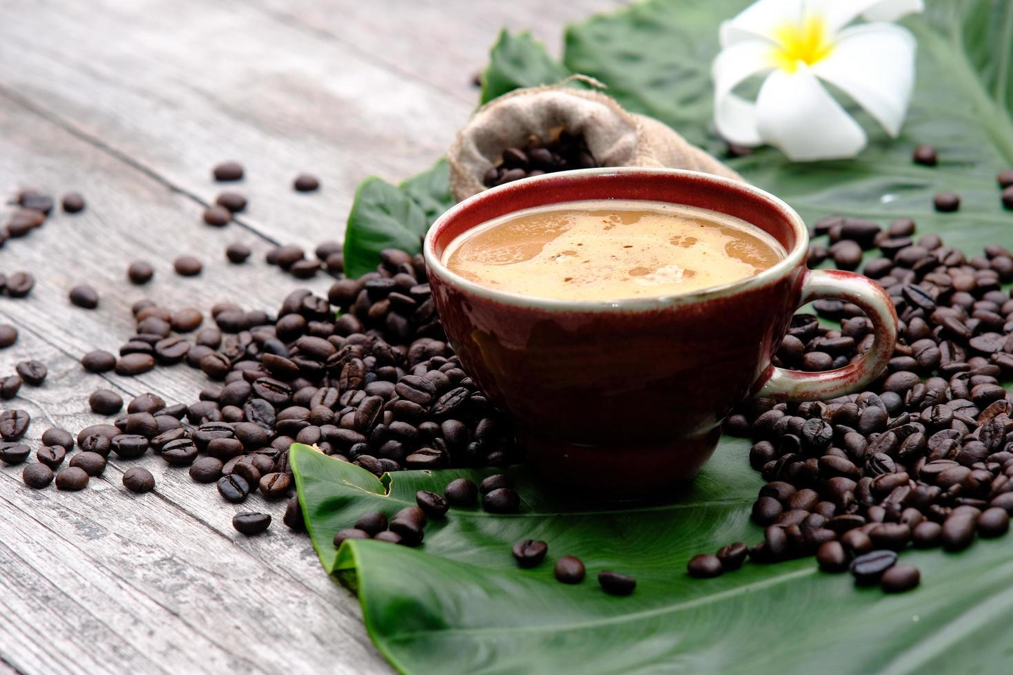 xícara de café em fundo de madeira com grãos de café foto