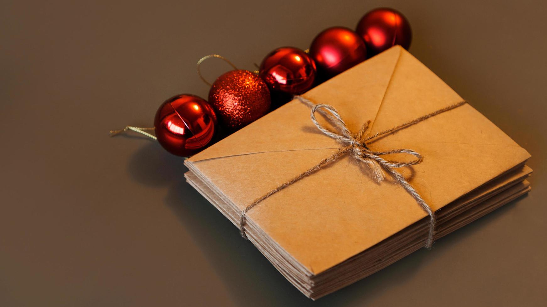 composição de natal. envelopes artesanais e bolas vermelhas. pilha de cartas foto