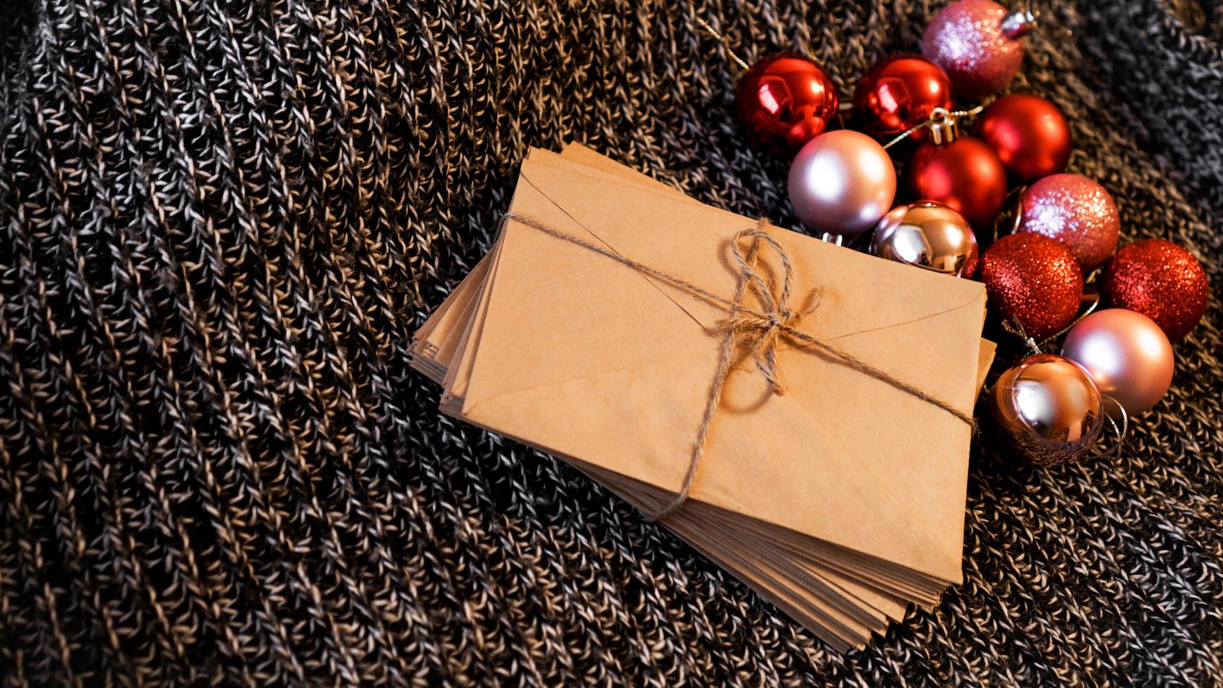 pilha de cartas de papel artesanal com bolas vermelhas e rosa de natal foto