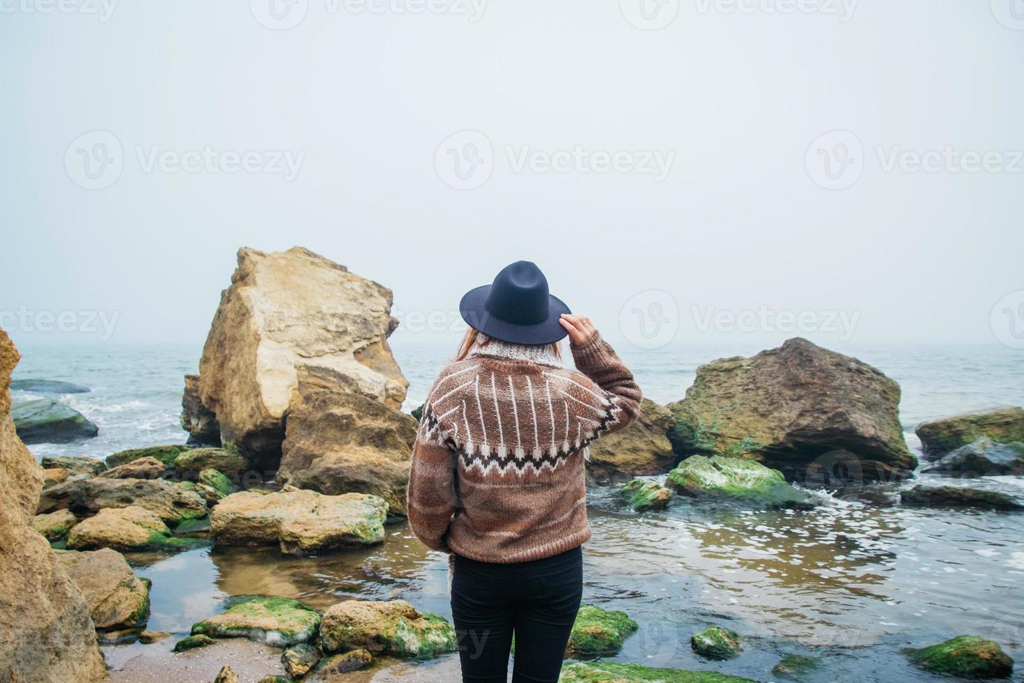 retrato de jovem com chapéu em uma rocha contra um lindo mar foto