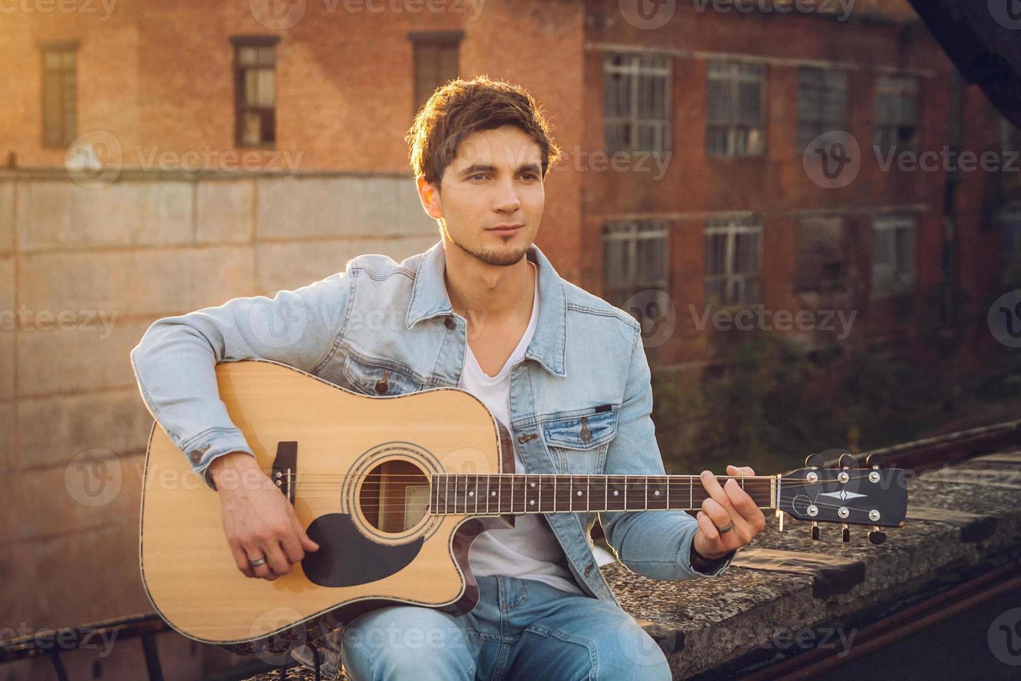 jovem tocando guitarra na cidade em fundo de raios de sol foto