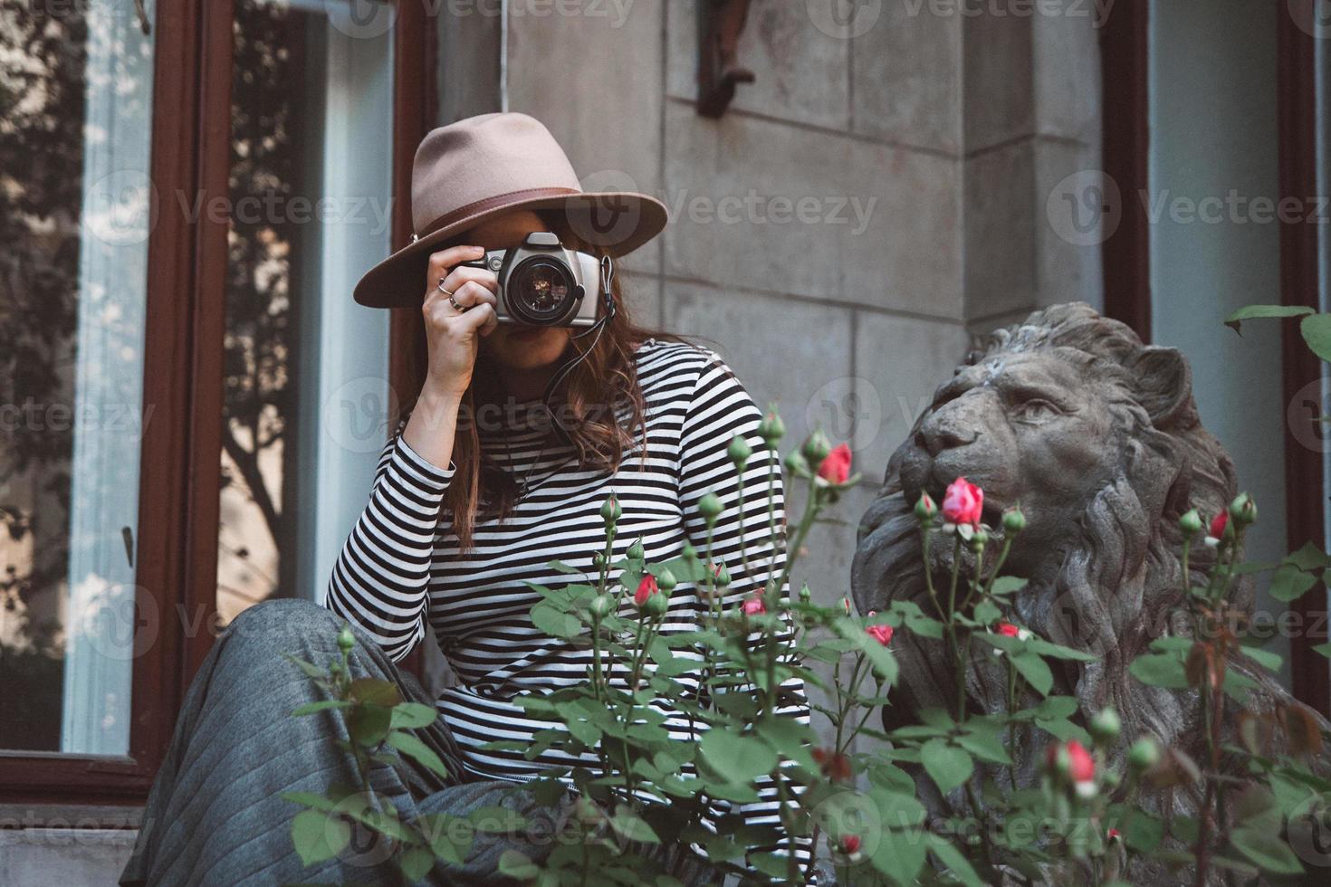 linda mulher com chapéu tira uma foto com câmera antiquada