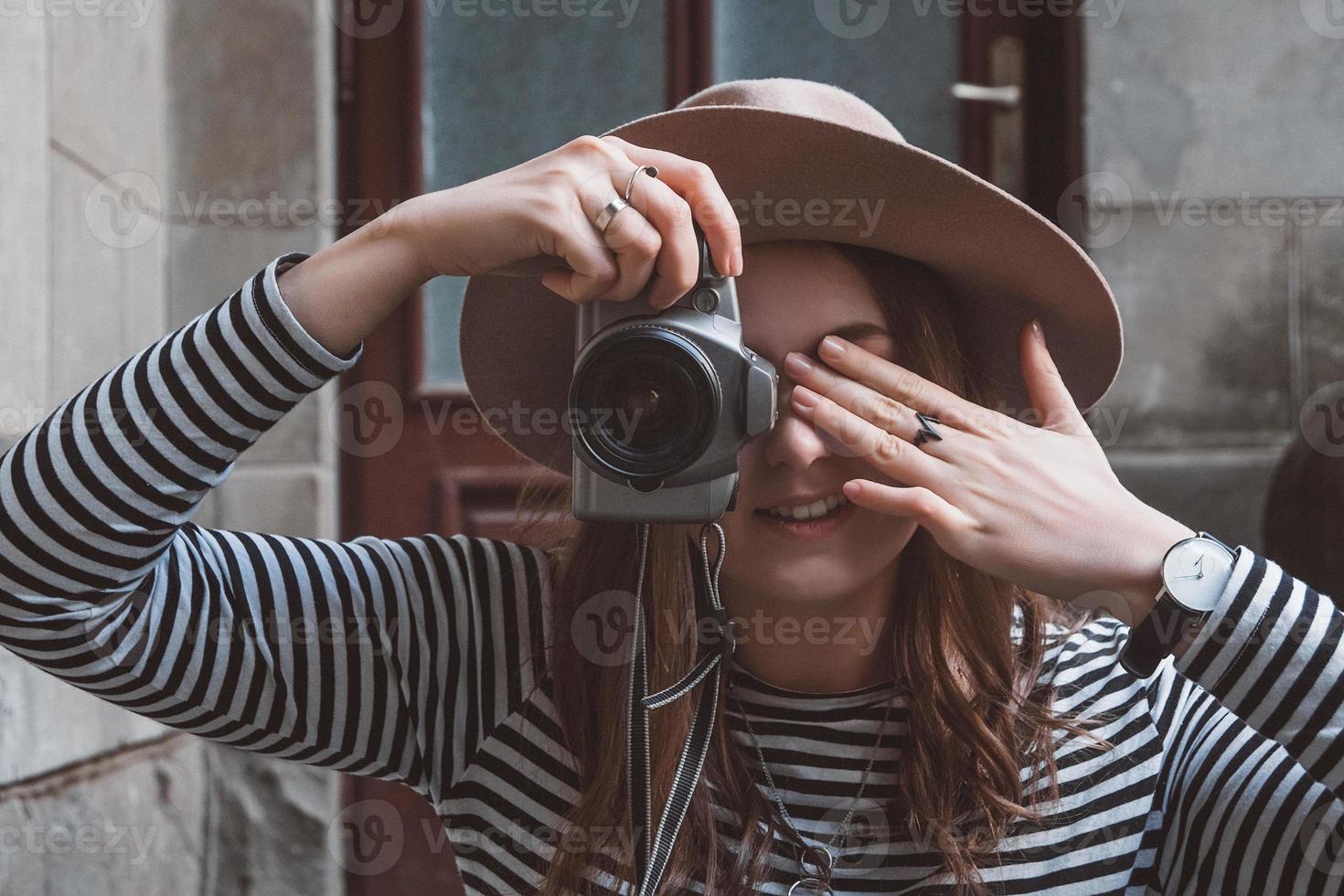 linda mulher com chapéu tirando foto com a câmera antiga