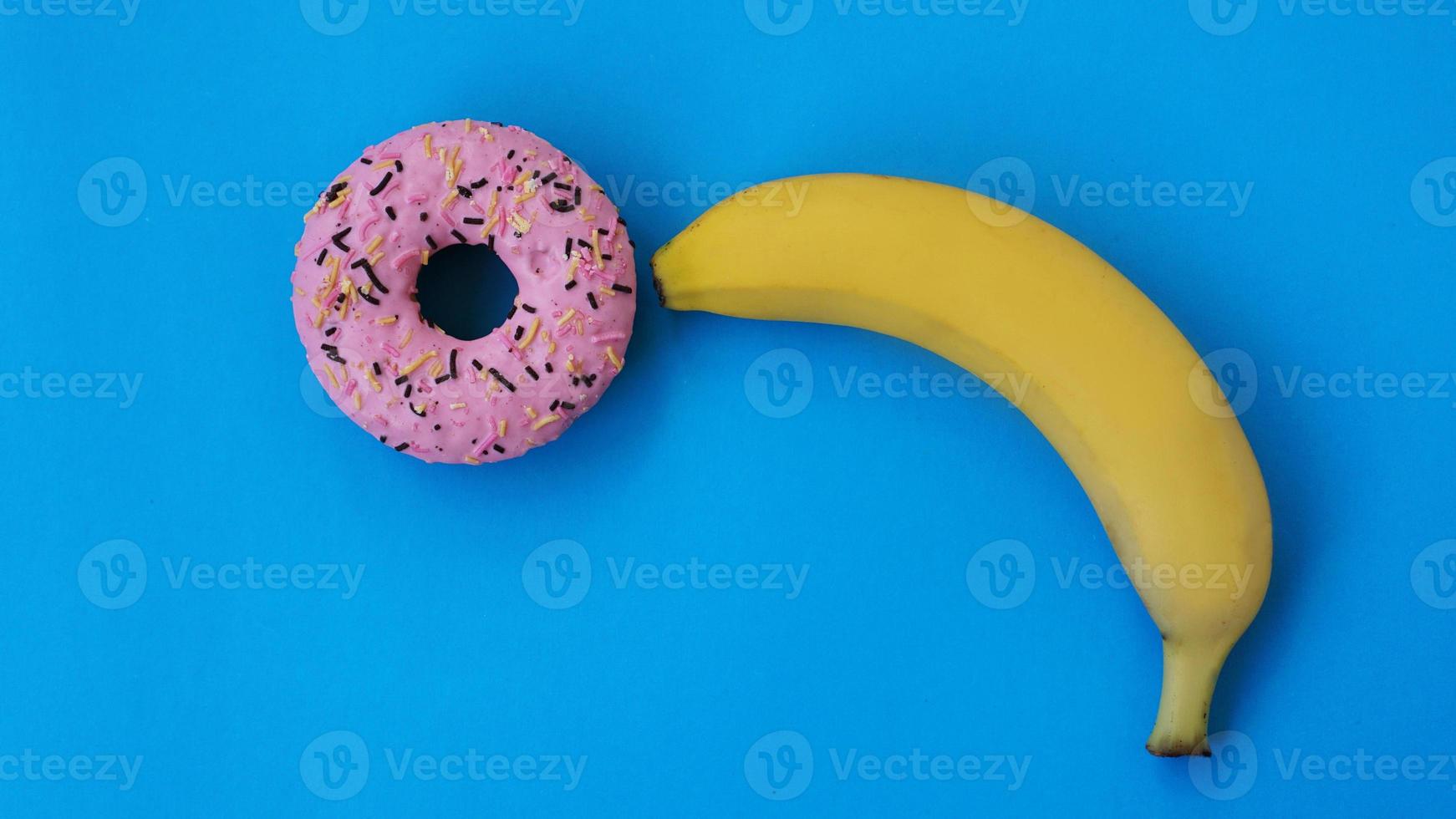 rosquinha doce e banana em fundo de cor azul foto