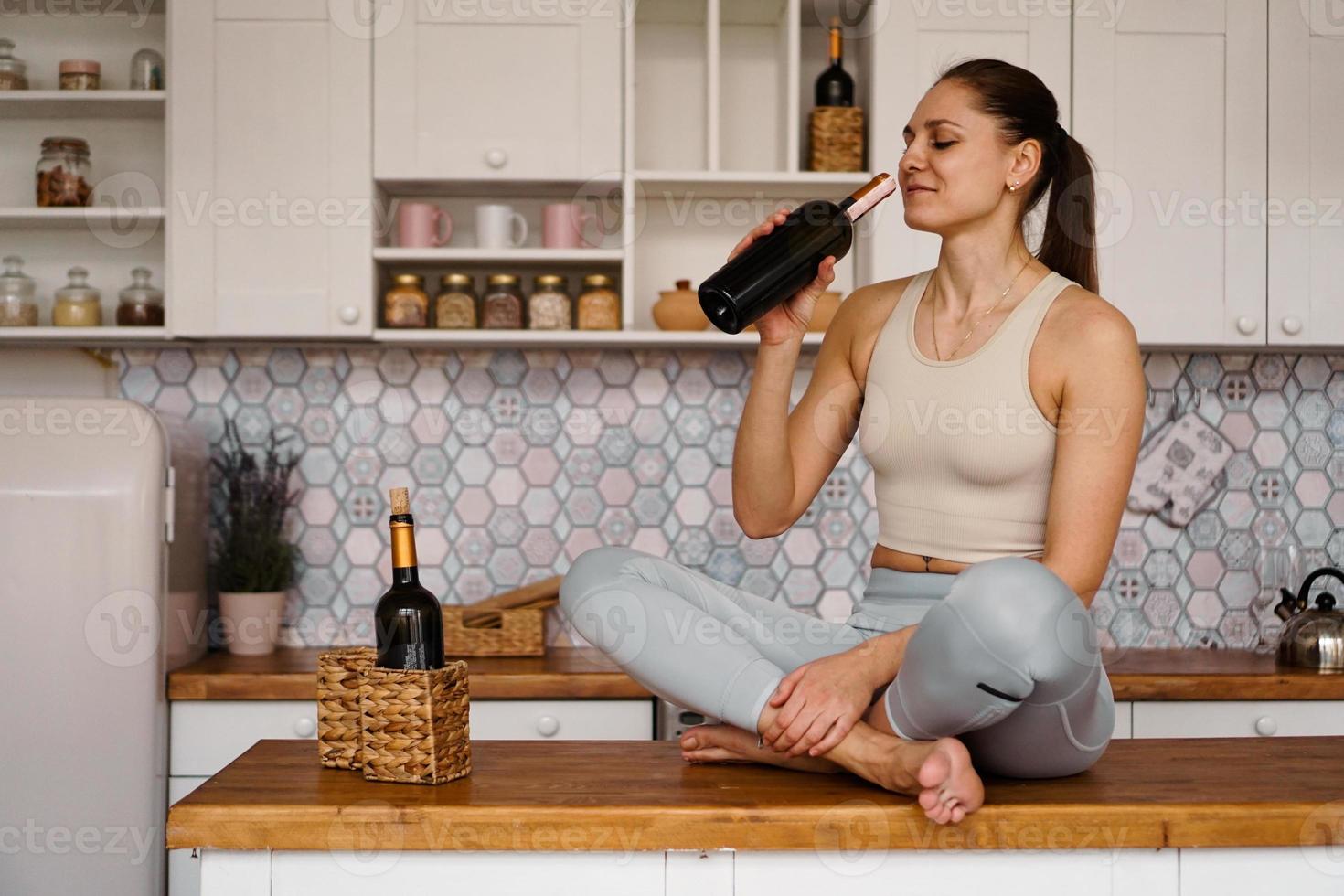 Mulher atlética em um agasalho em uma cozinha leve bebidas foto