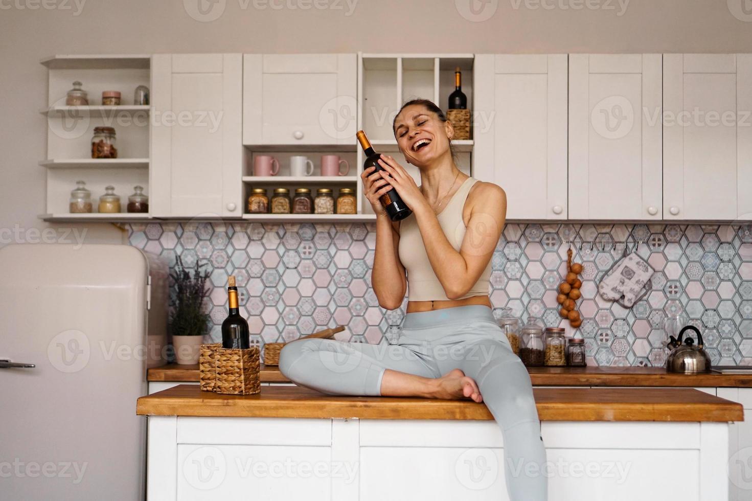 mulher em um agasalho em uma cozinha leve bebe vinho tinto foto