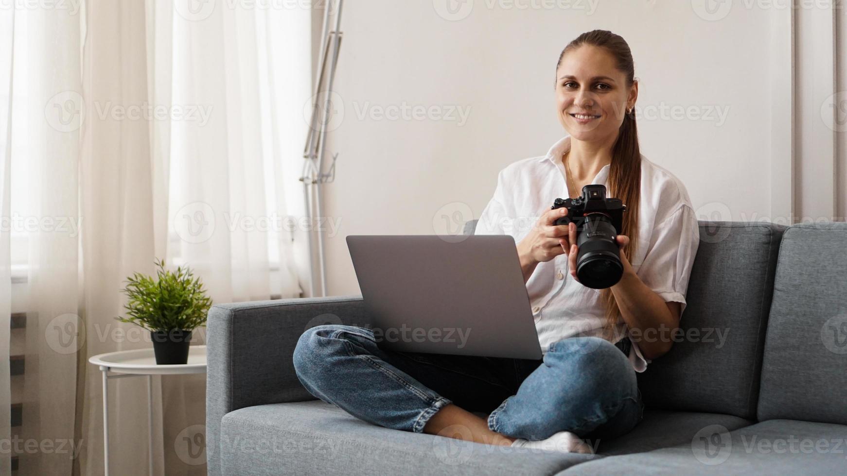 jovem feliz com câmera fotográfica usando laptop em casa foto