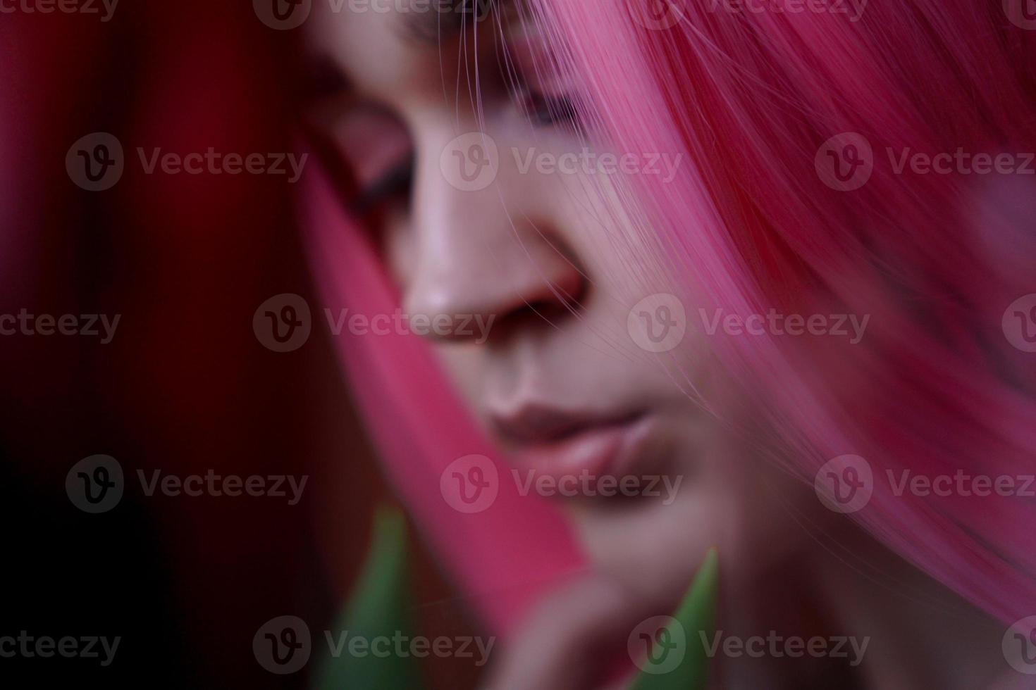 garota de cabelo rosa com flores perto do rosto foto