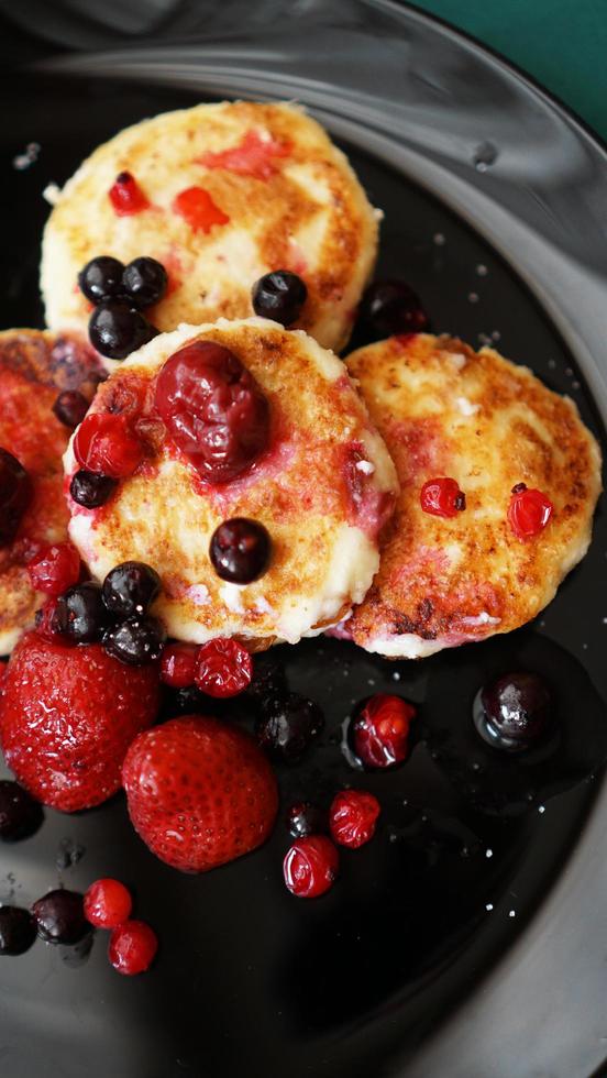 panquecas de queijo com frutas em uma placa preta. foto