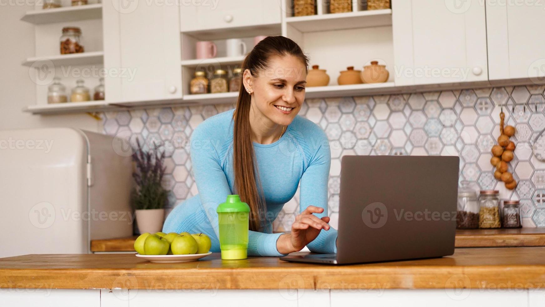 mulher sorridente usando computador em cozinha moderna foto