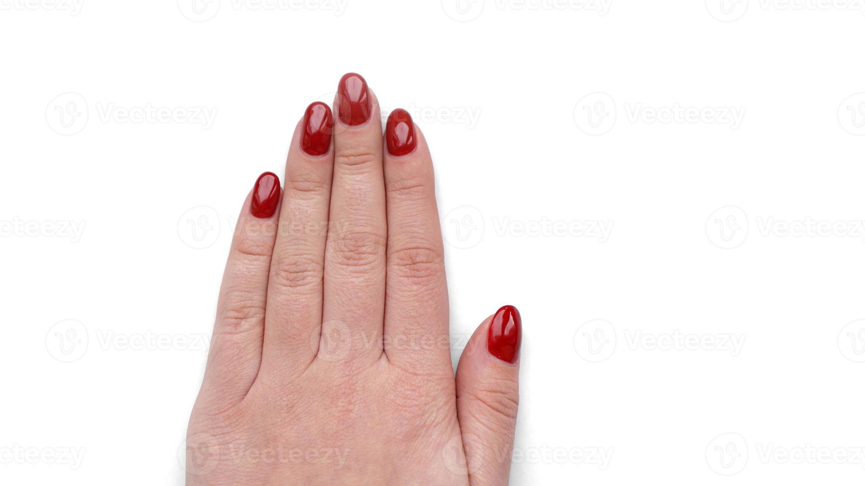 linda mão feminina com manicure vermelha e unha isolada no branco foto