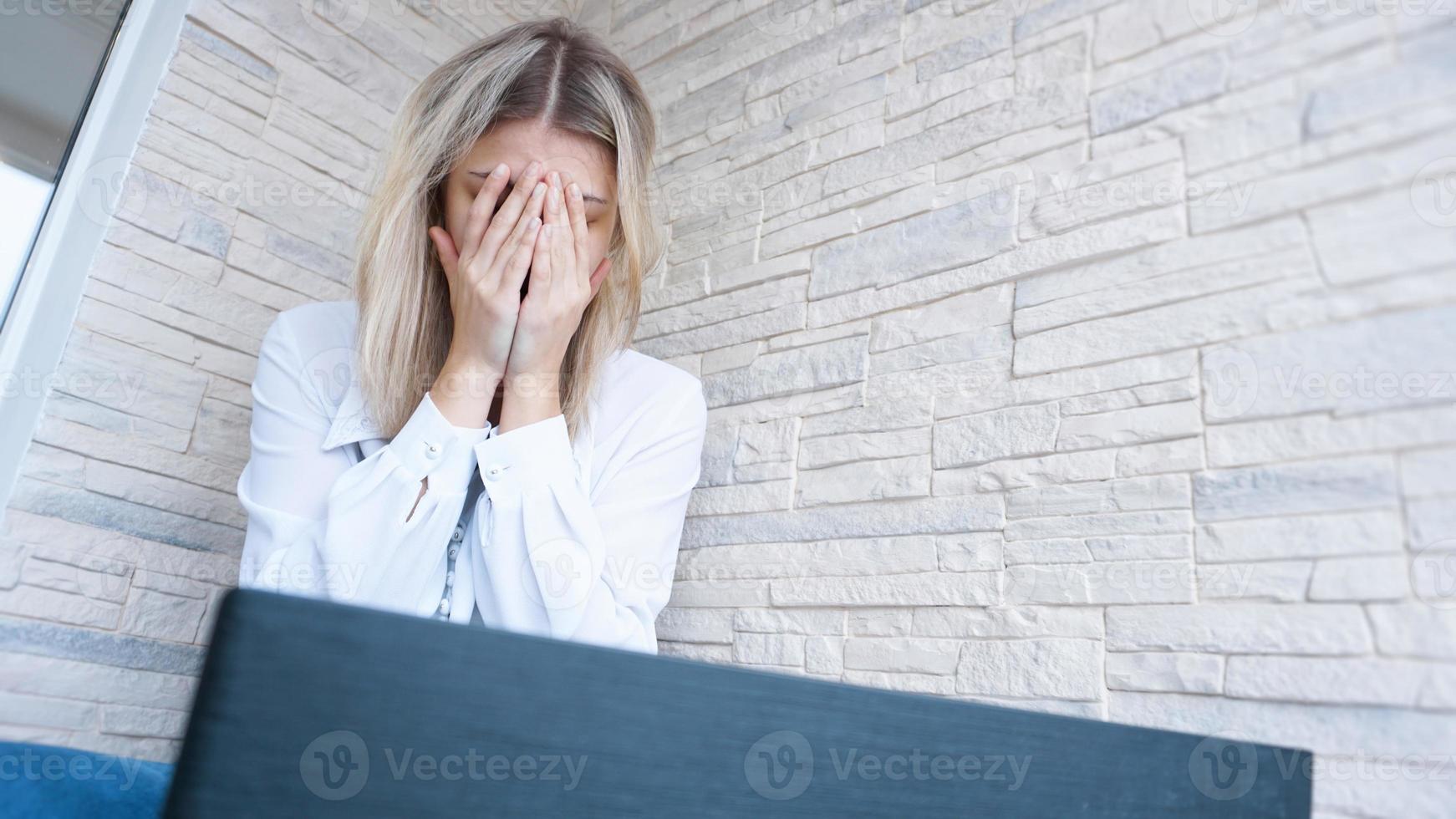 mulher olha para o laptop com uma expressão de preocupação e dor foto