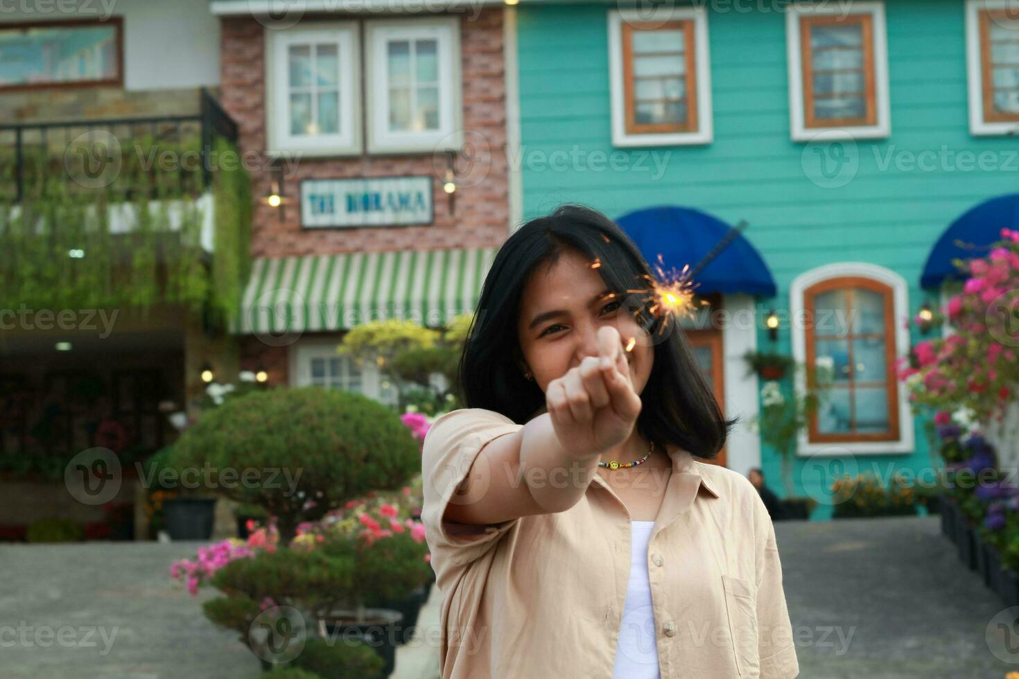 feliz jovem ásia mulher segurando diamante apreciar Novo ano véspera celebração dentro ao ar livre jardim do colorida vintage casa dentro tarde foto