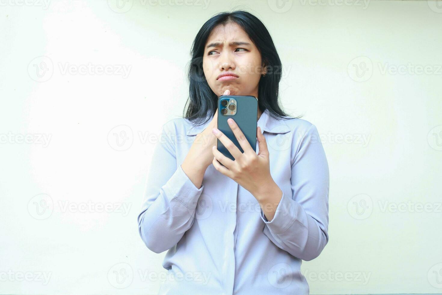 retrato do preocupado ásia jovem o negócio mulher pensando a sério usando Smartphone com dedo em queixo olhando ausente, triste fêmea com receoso expressão vestindo formal terno isolado dentro branco fundo foto