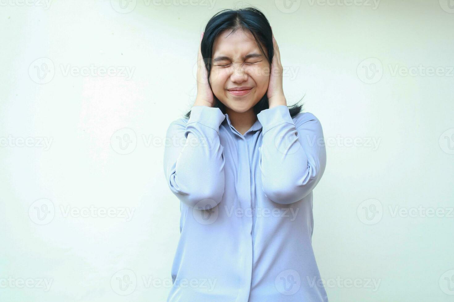 depressivo ásia jovem o negócio mulher cobertura orelhas e cabeça com fechadas olho, excesso de trabalho fêmea estressado vestindo formal roxa camisa em pé isolado sobre branco fundo foto