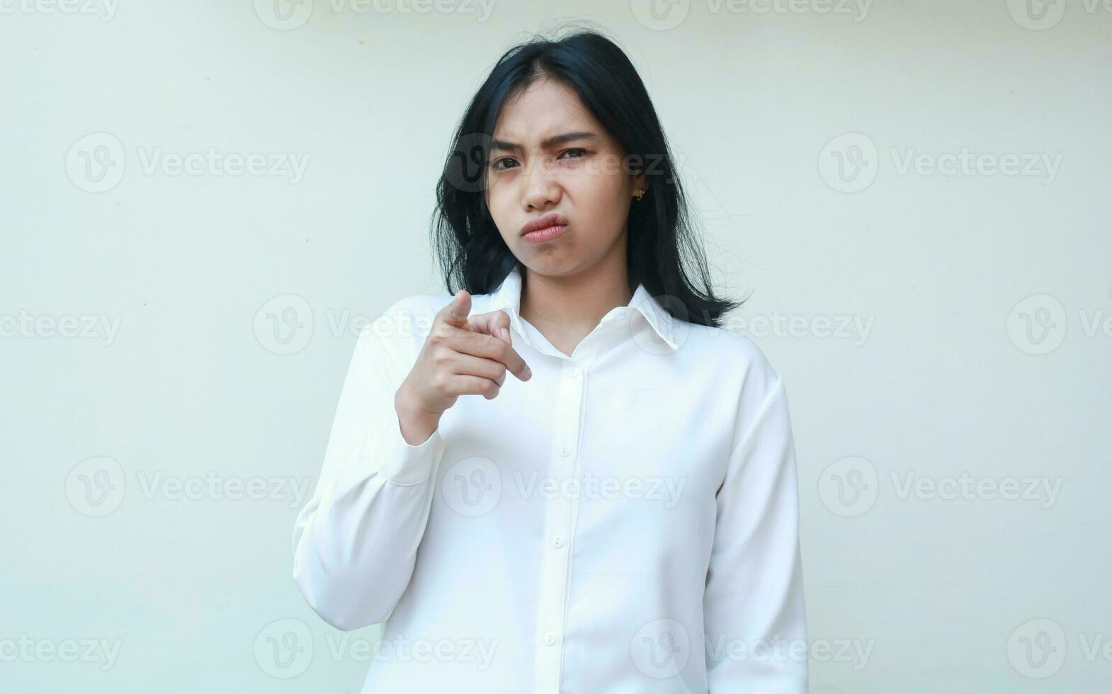 estúdio tiro do chateado jovem ásia mulher Gerente apontando para Câmera com infeliz face expressão Faz culpar você gesto para erros problema vestindo branco formal camisa isolado om branco fundo foto