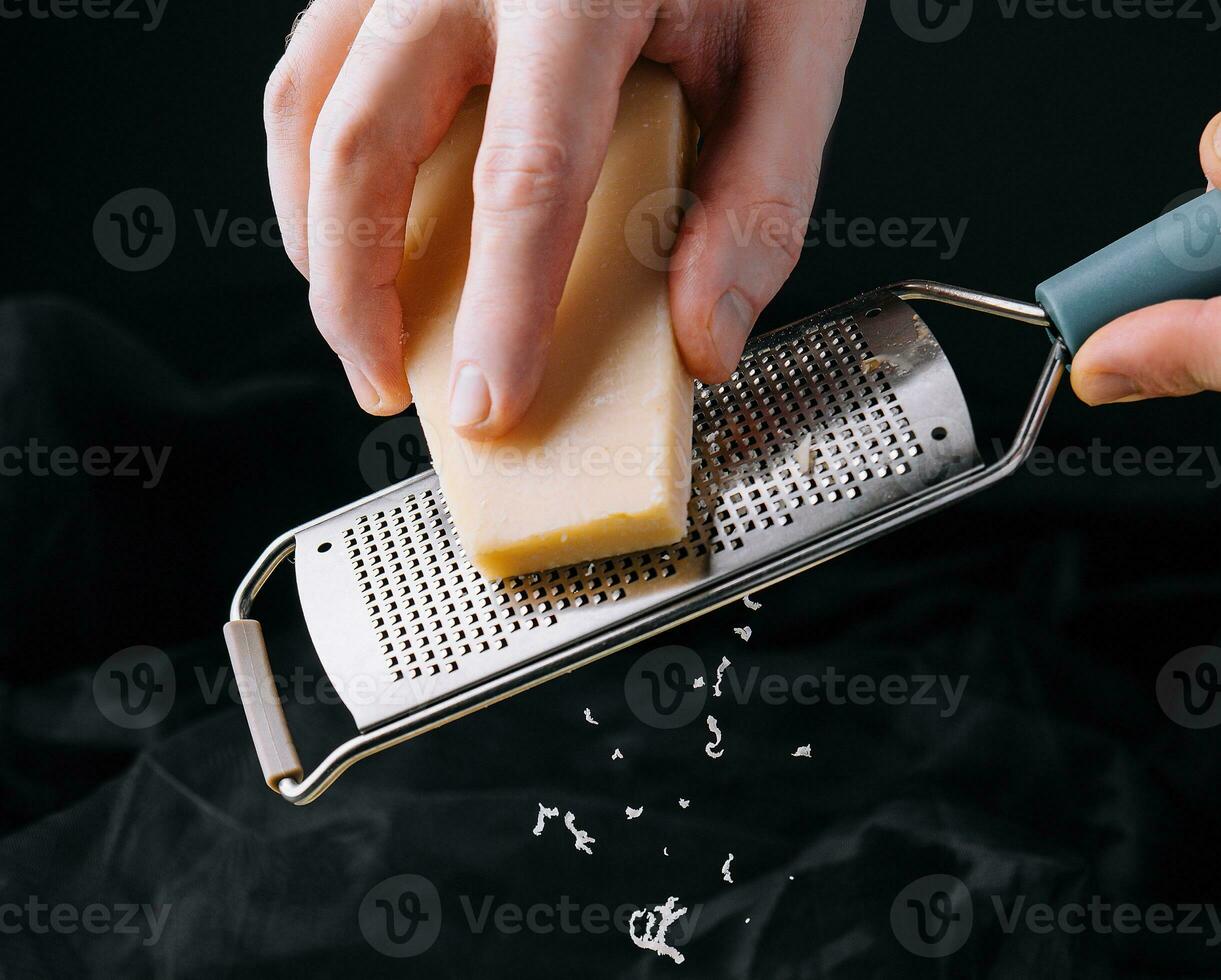 mão do a cozinhar esfrega a queijo em uma ralador. foto