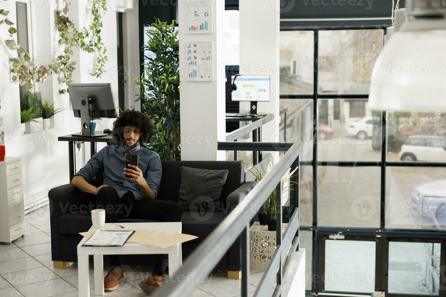 jovem árabe financeiro analista usando Smartphone dentro começar acima unicórnio o negócio escritório. companhia executivo Gerente mensagens de texto conectados com Móvel telefone enquanto relaxante dentro coworking espaço foto