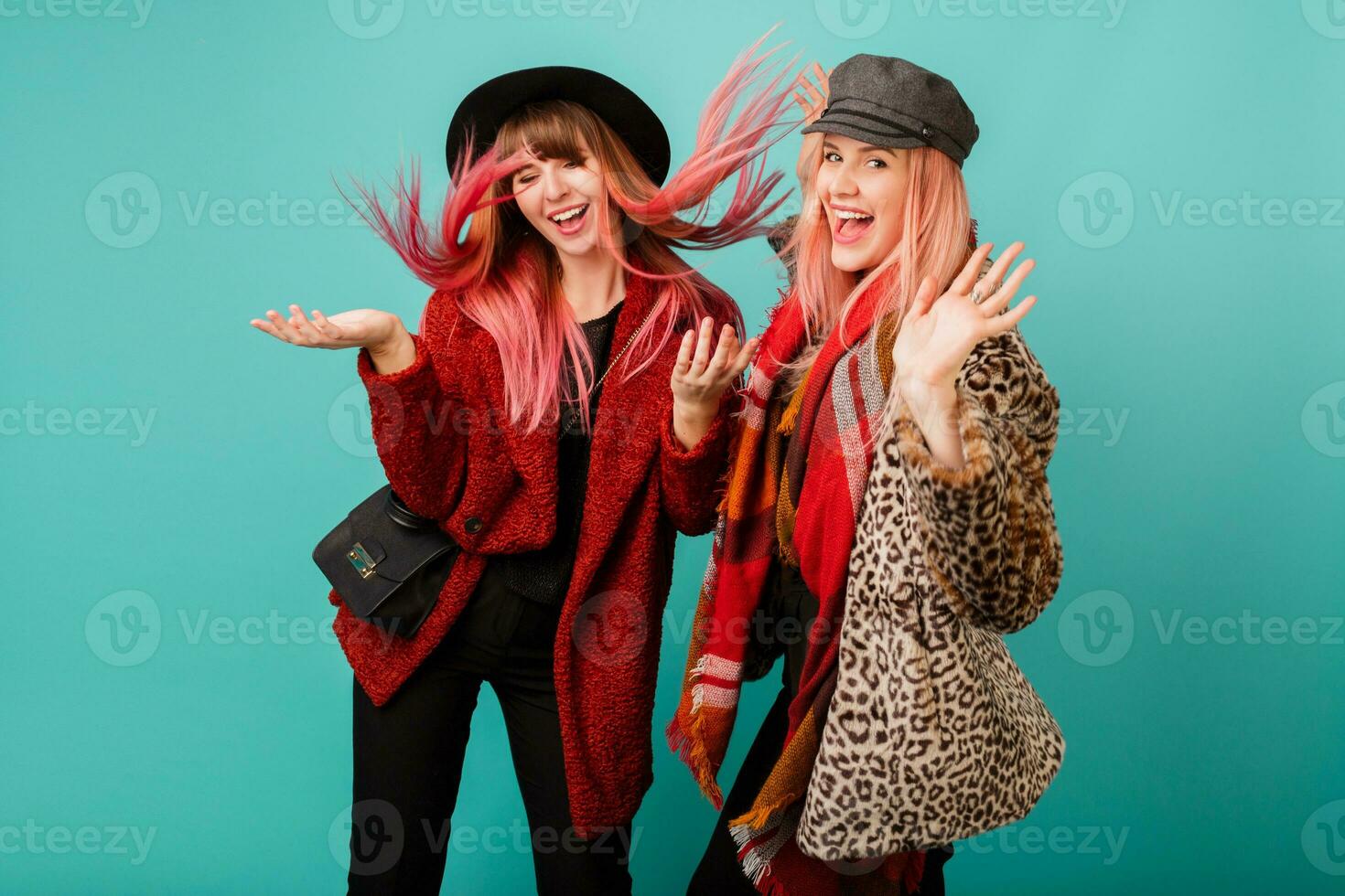 dois lindo branco mulheres dentro à moda leopardo impressão falso pele casaco e lã cachecol posando em turquesa fundo. elegante inverno roupa. estúdio tomada. foto