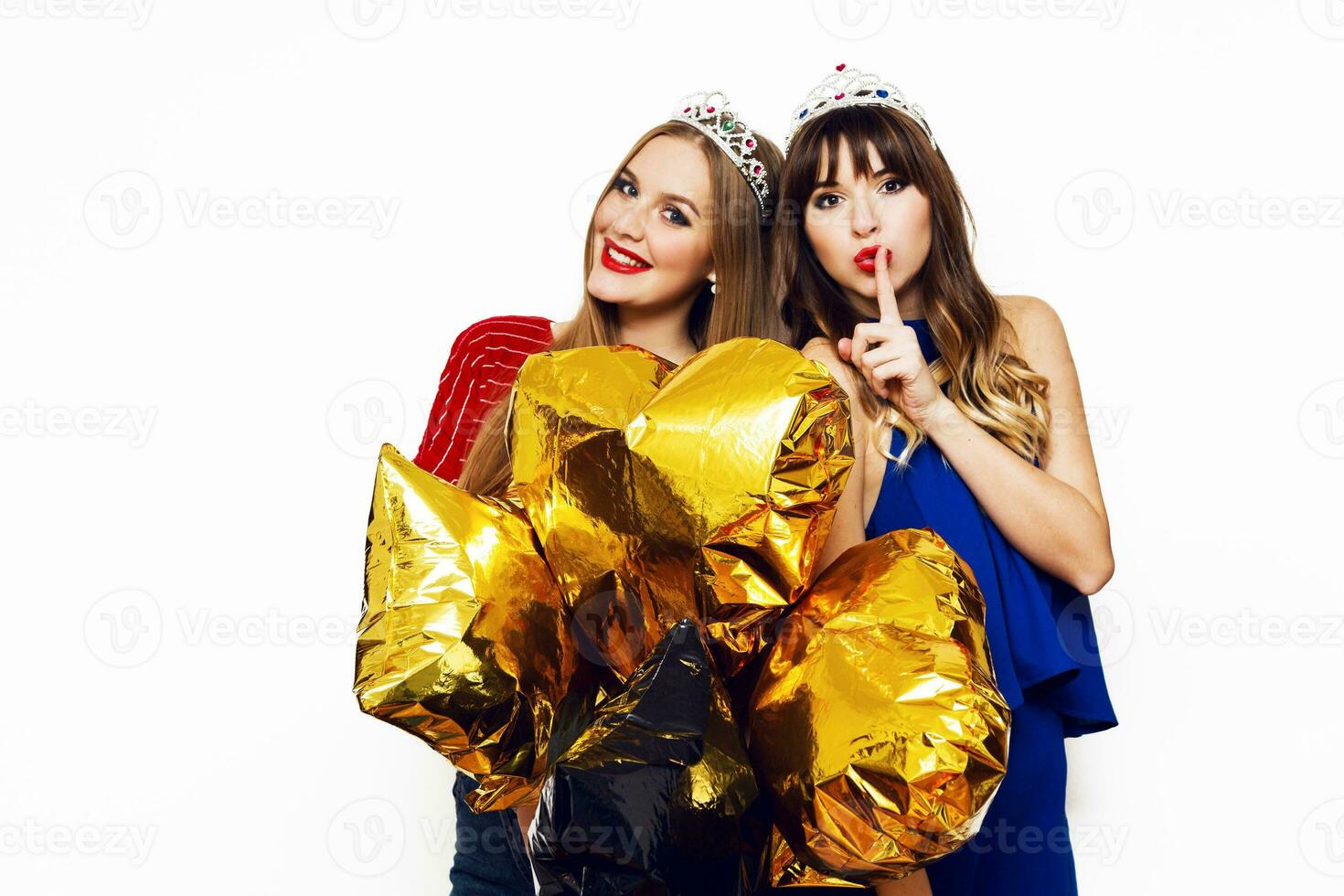 dois feliz adorável jovem mulheres com ouro Estrela em forma balões dentro mascarada coroa tendo Diversão , posando em branco fundo. a comemorar aniversário, Novo ano . foto