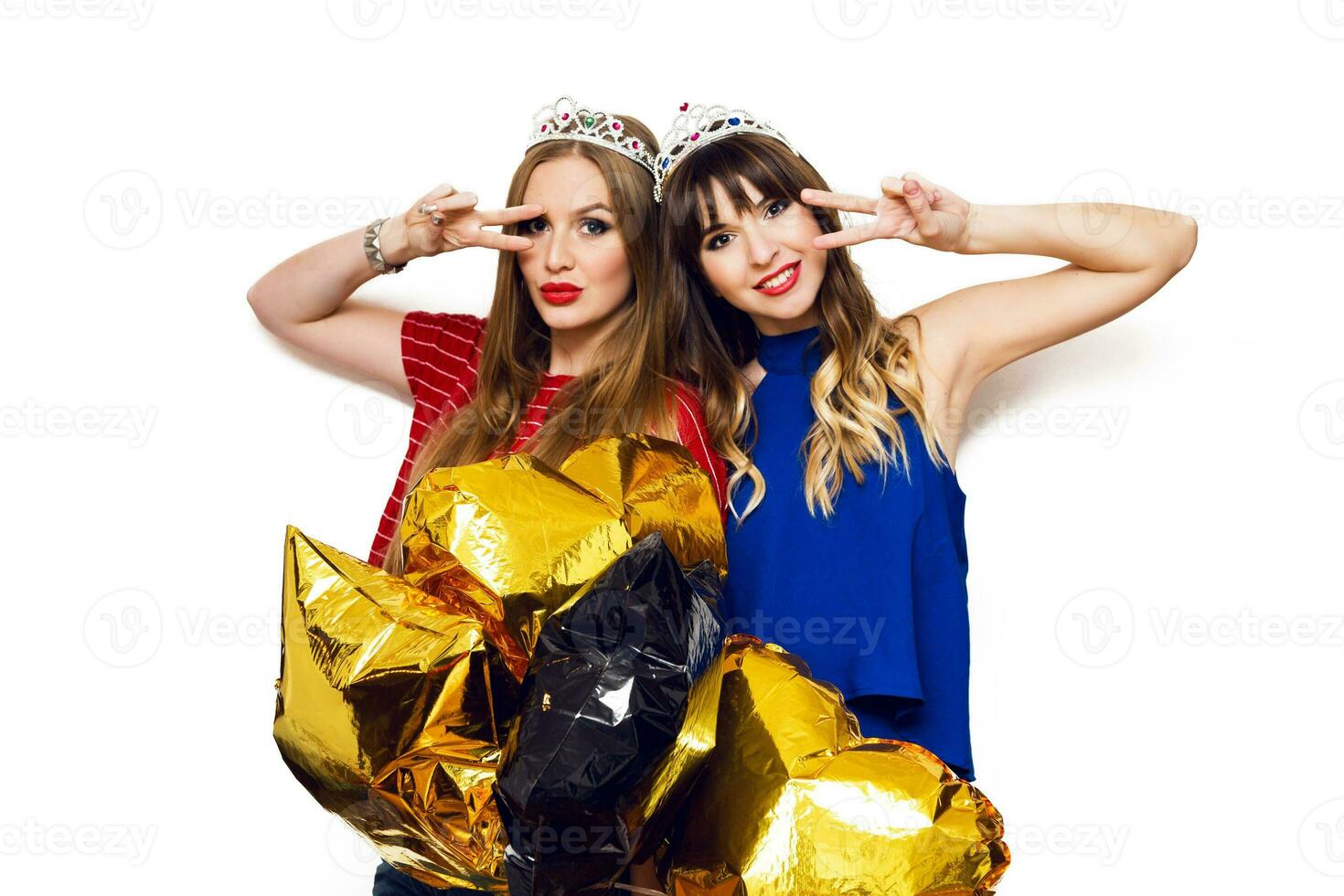 dois feliz adorável jovem mulheres com ouro Estrela em forma balões dentro mascarada coroa tendo Diversão , posando em branco fundo. a comemorar aniversário, Novo ano . foto