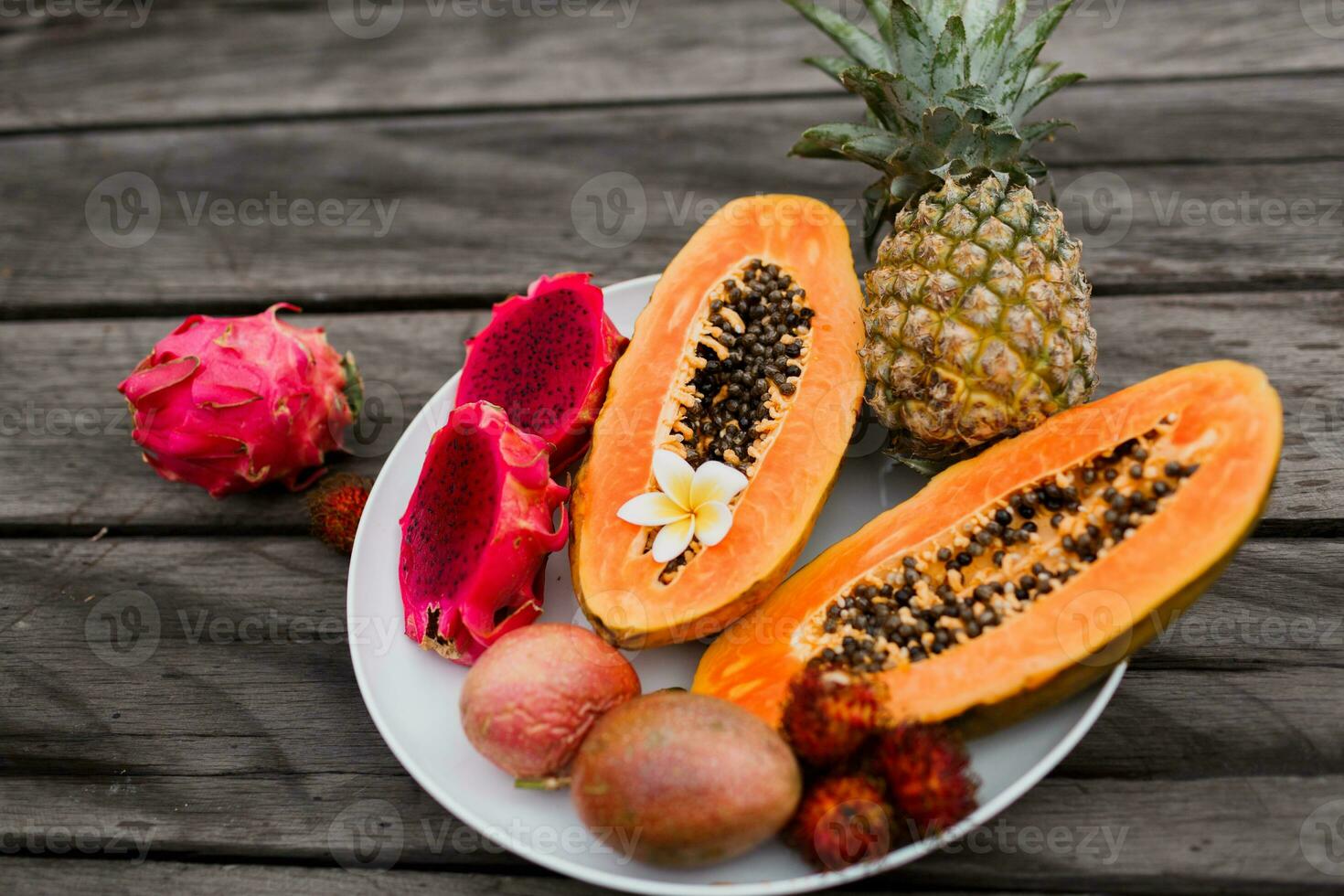 fechar acima imagem do fruta trança com fatias do mamão, Dragão fruta e abacaxi em madeira mesa. foto