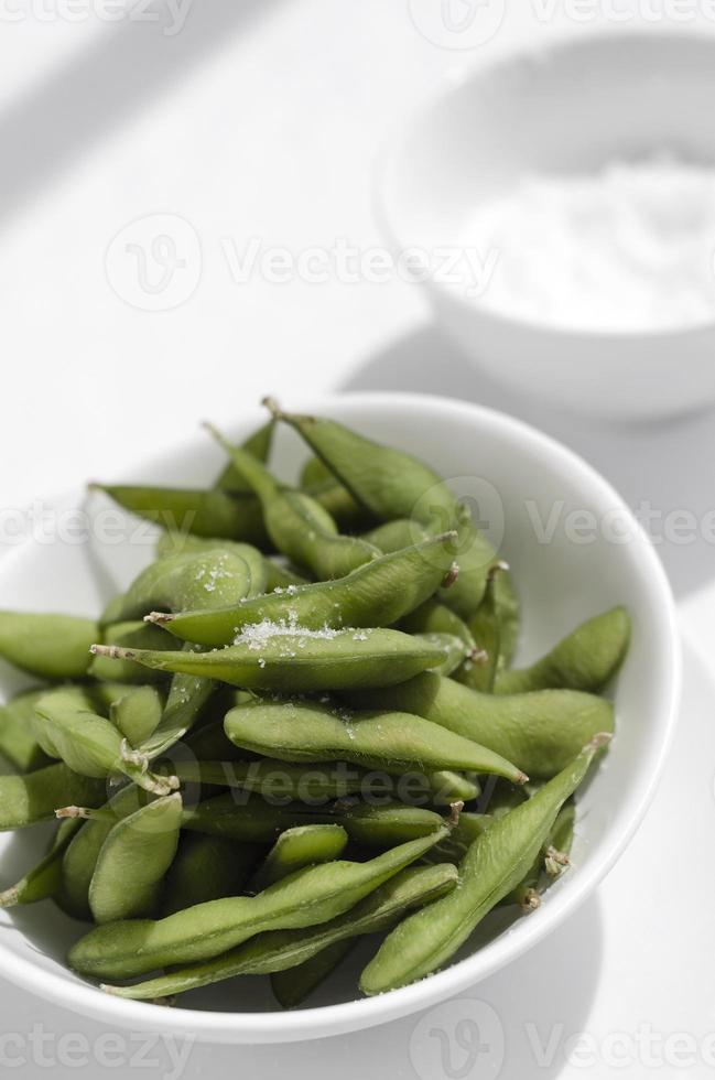 lanche de feijão edamame orgânico em uma tigela na mesa com sal marinho foto