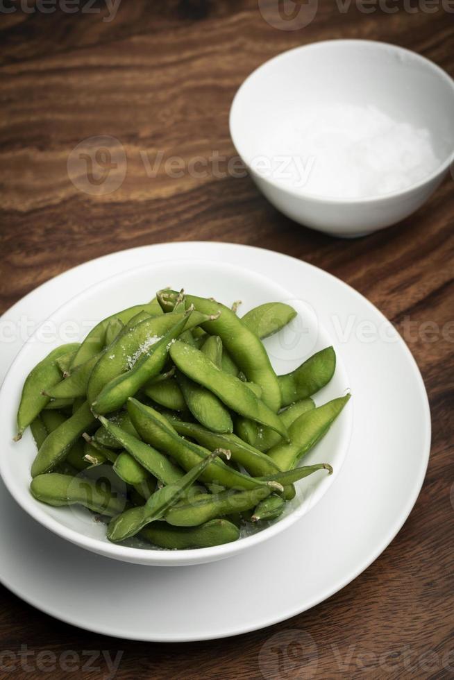 lanche de feijão edamame orgânico em uma tigela na mesa com sal marinho foto