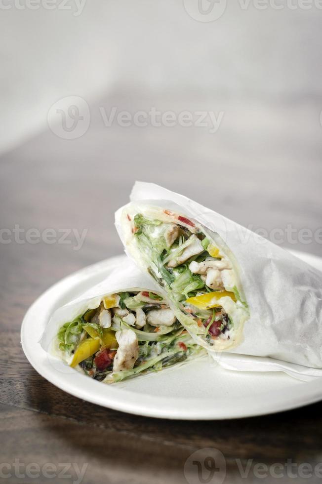 Envolvimento de salada de frango orgânico em papel branco no fundo da mesa de madeira foto