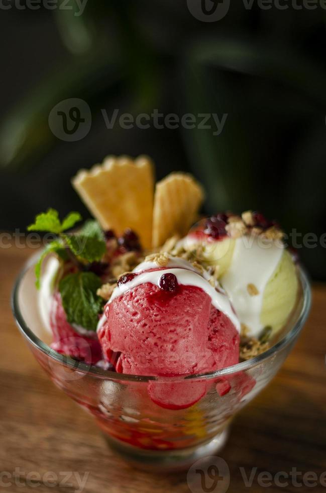 Sorvete de morango e pistache sorvete de sobremesa sundae em uma tigela na mesa de madeira foto