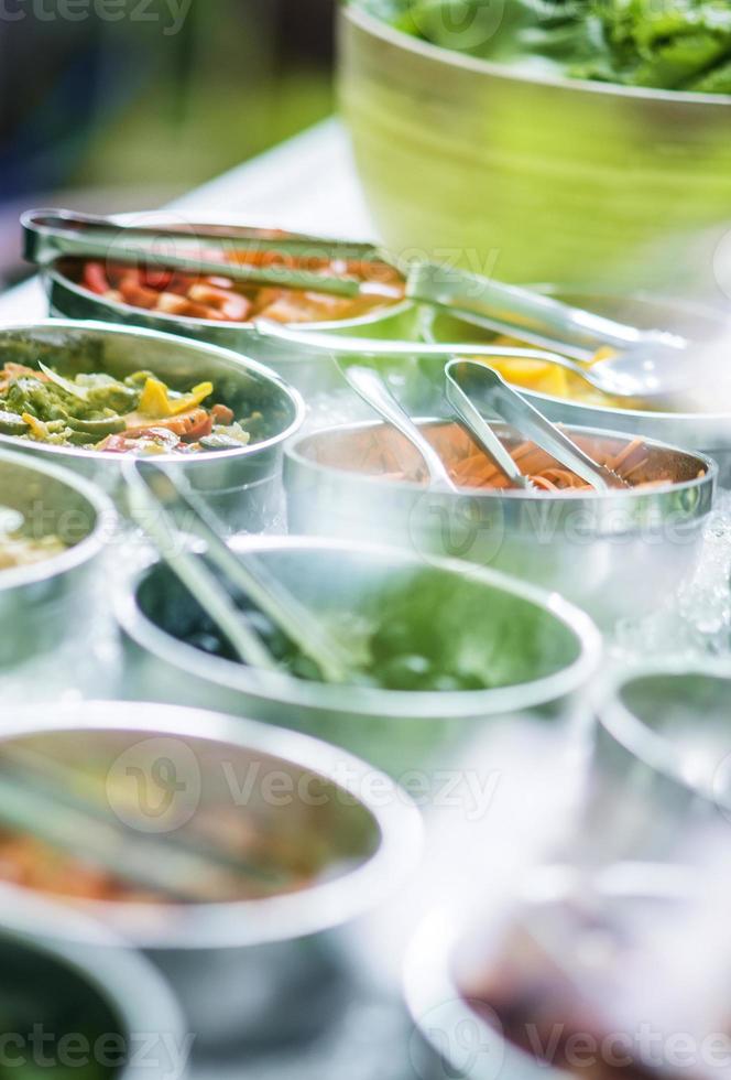 tigelas de pimentas vermelhas orgânicas frescas e vegetais misturados em uma moderna vitrine de bufê de saladas foto