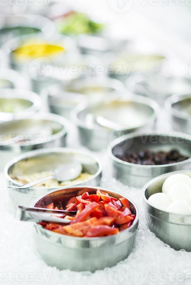 tigelas de pimentas vermelhas orgânicas frescas e vegetais misturados em uma moderna vitrine de bufê de saladas foto