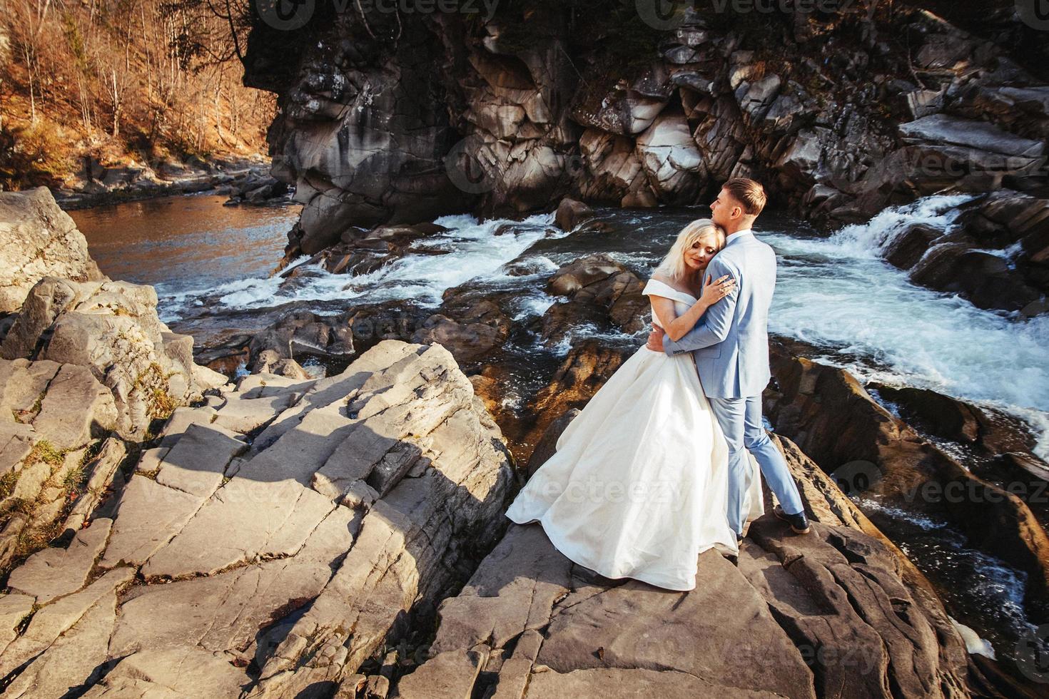 casal de noivos em um fundo de montanhas e rios no pôr do sol foto