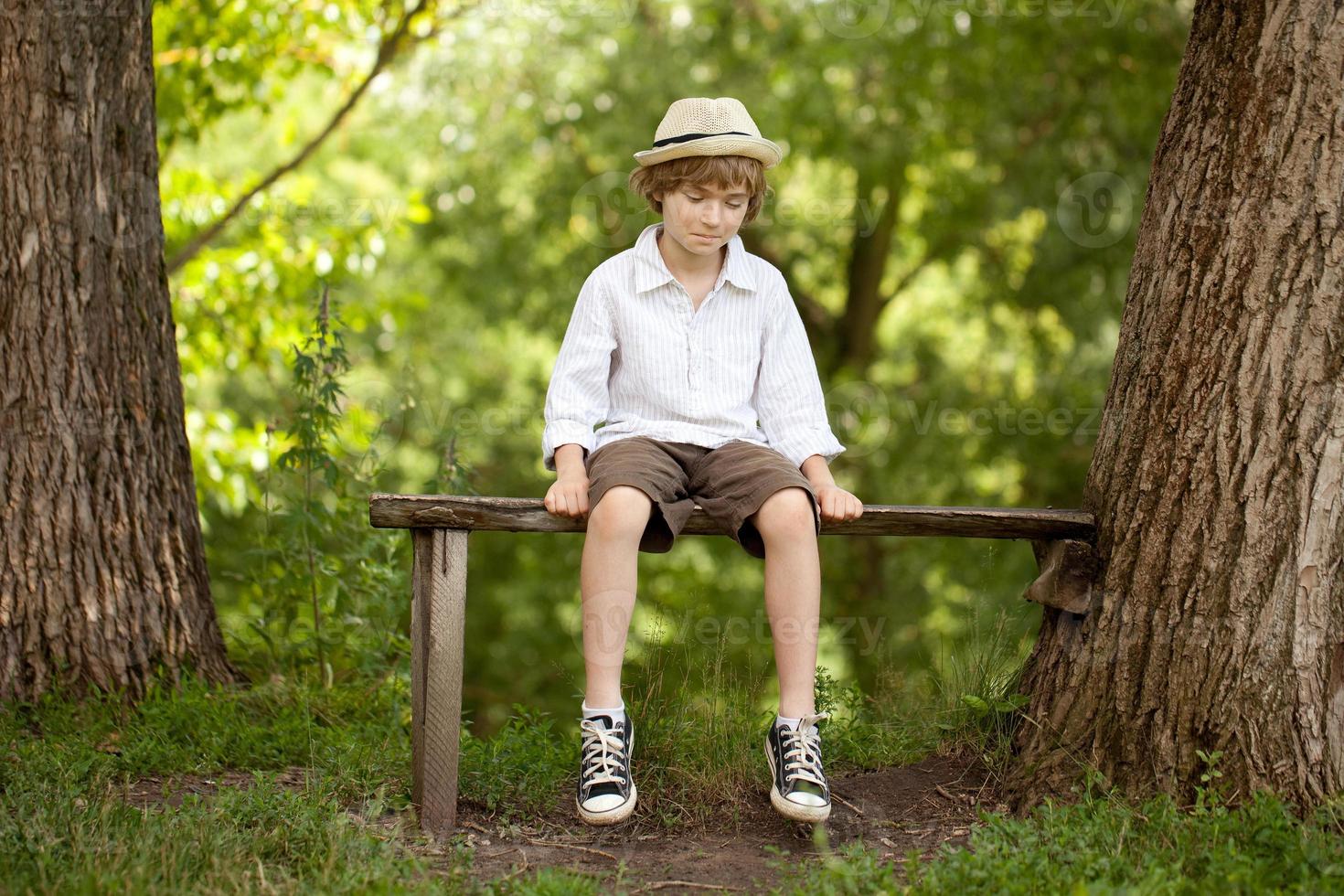 menino de cabelos louros de chapéu, camisa, shorts foto